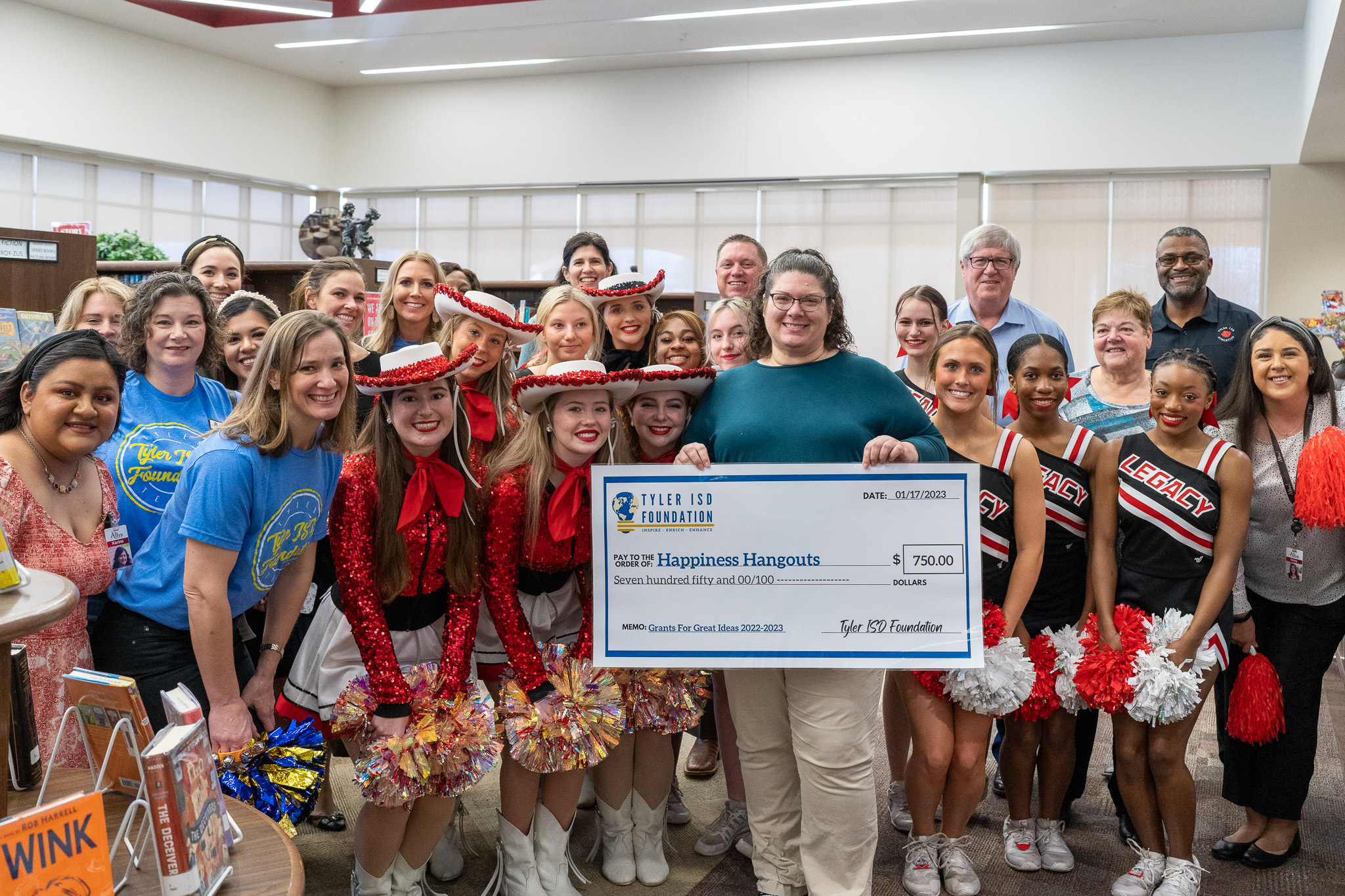 group of people standing in a hallway holding a giant check