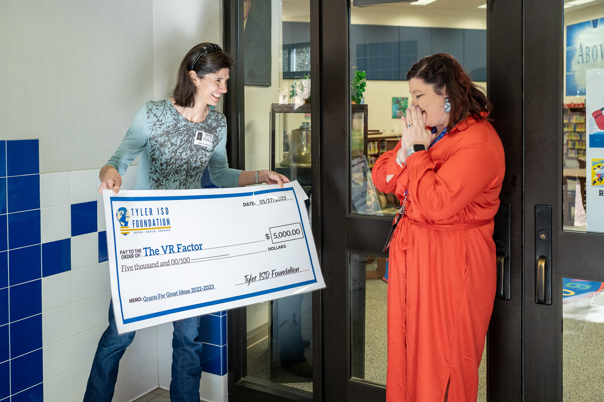 woman getting surprised with a giant check for a grant