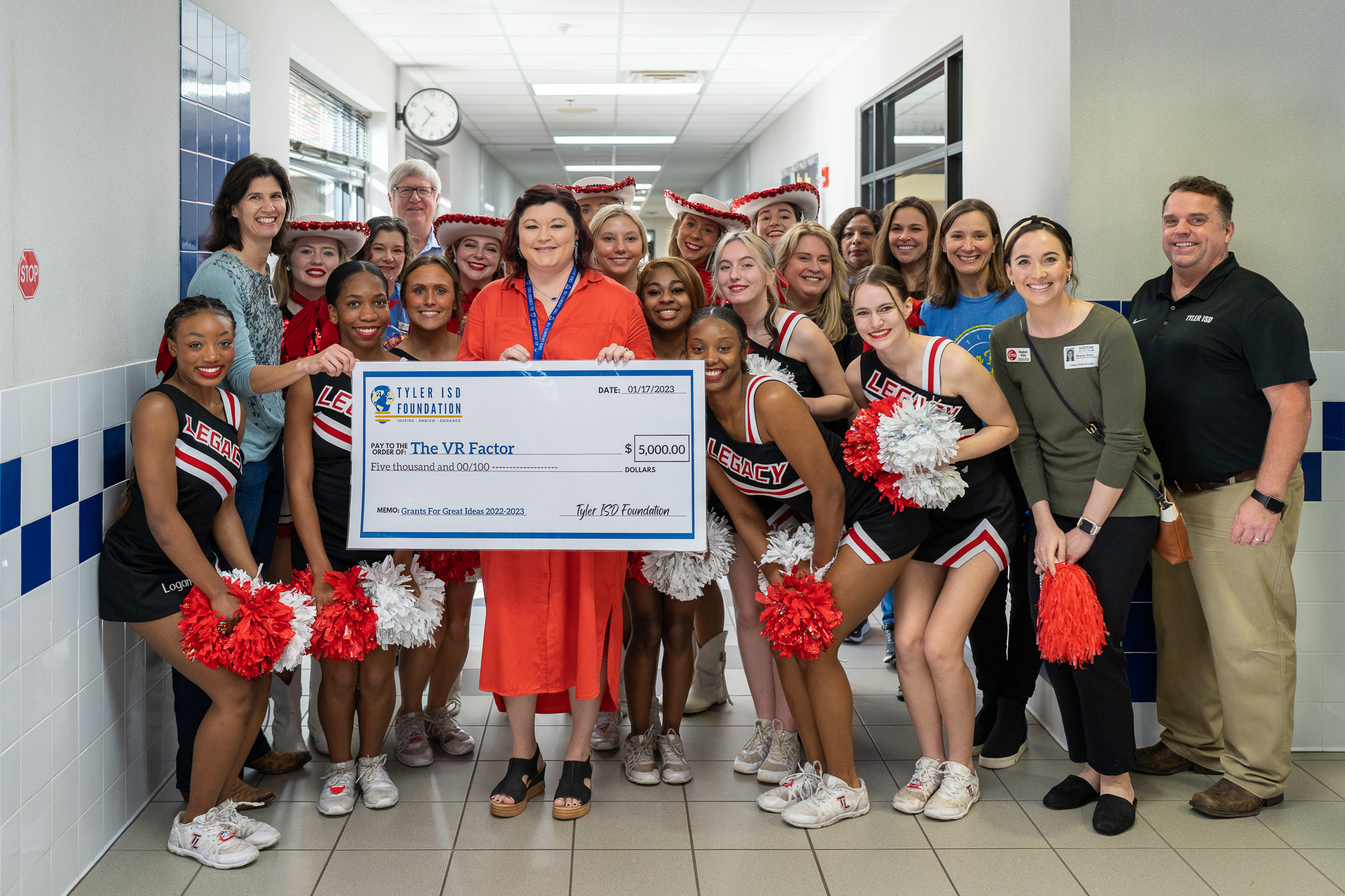 group of people standing in a hallway holding a giant check