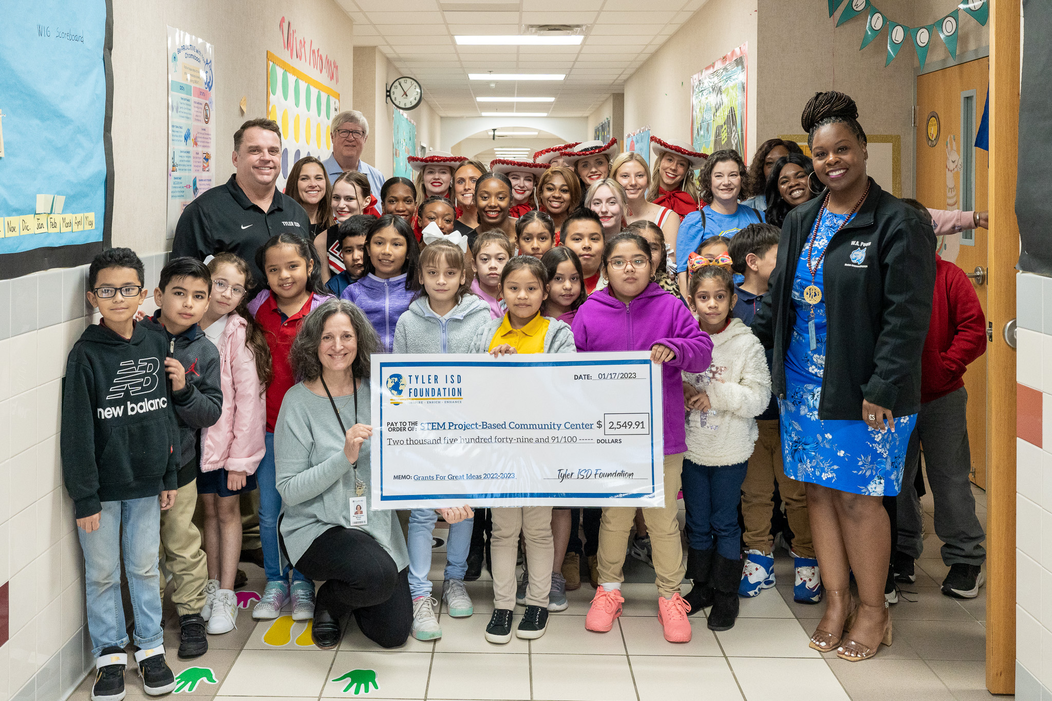 group of people standing in a hallway holding a giant check