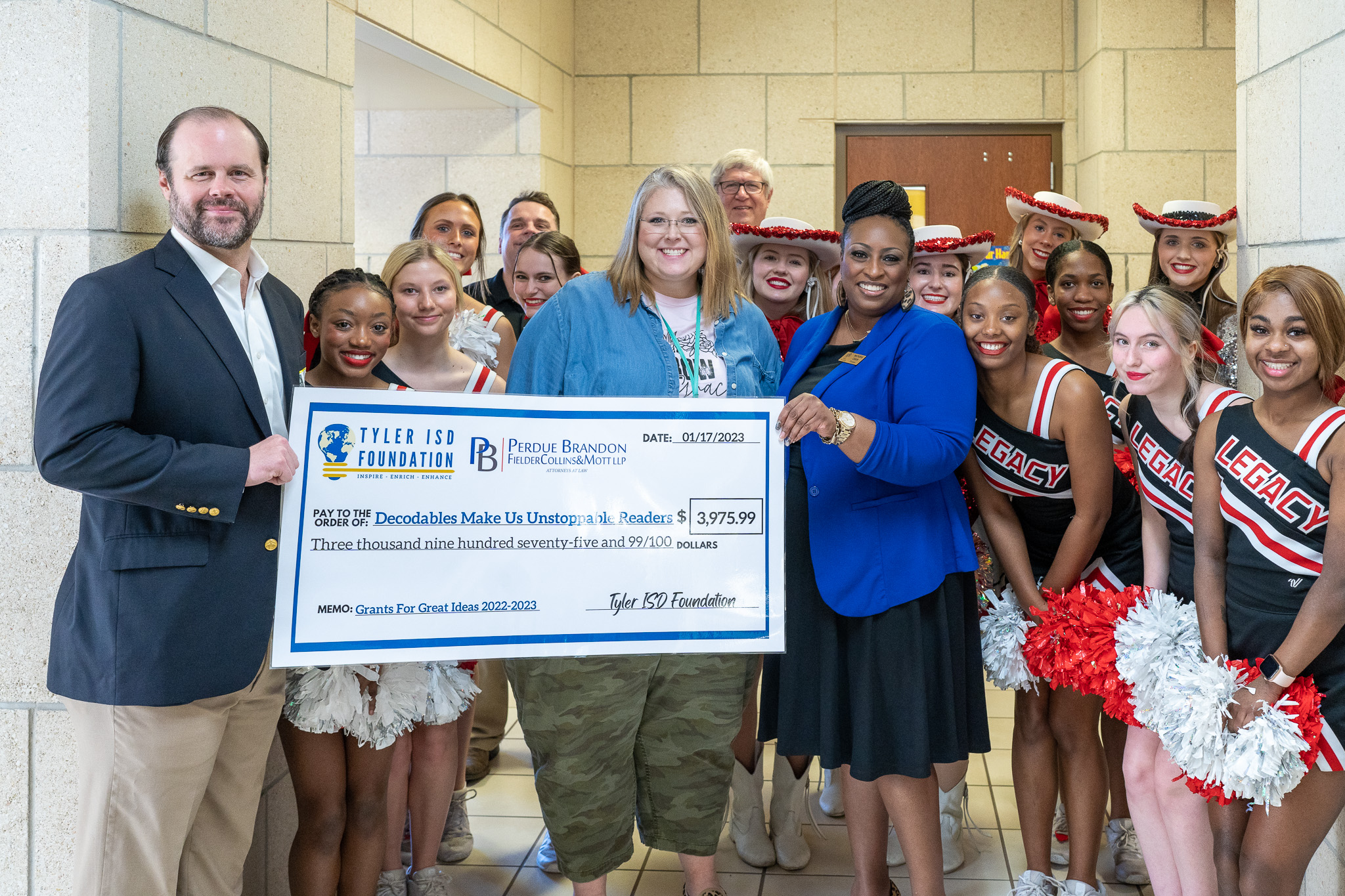 group of people standing in a hallway holding a giant check