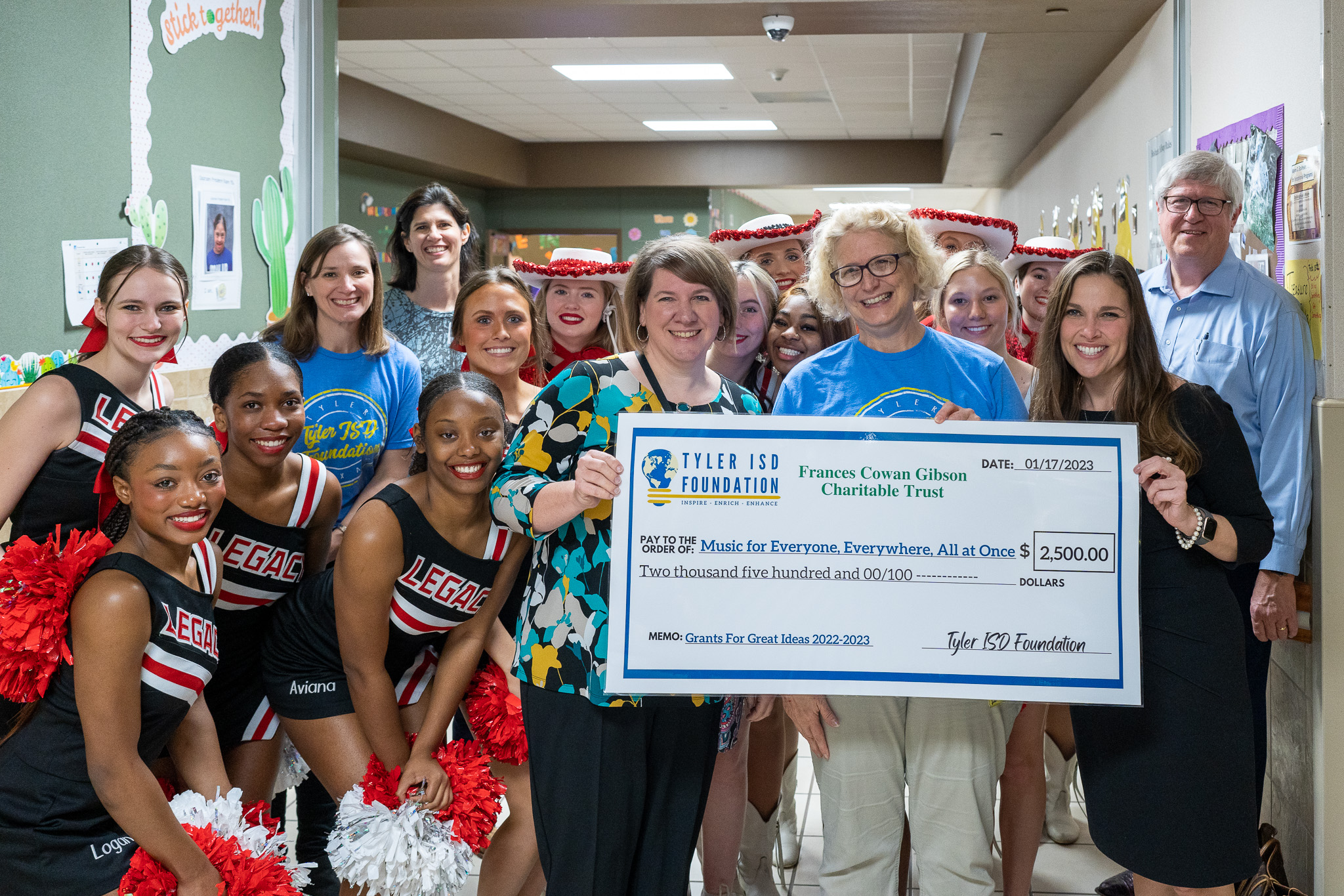 group of people standing in a hallway holding a giant check