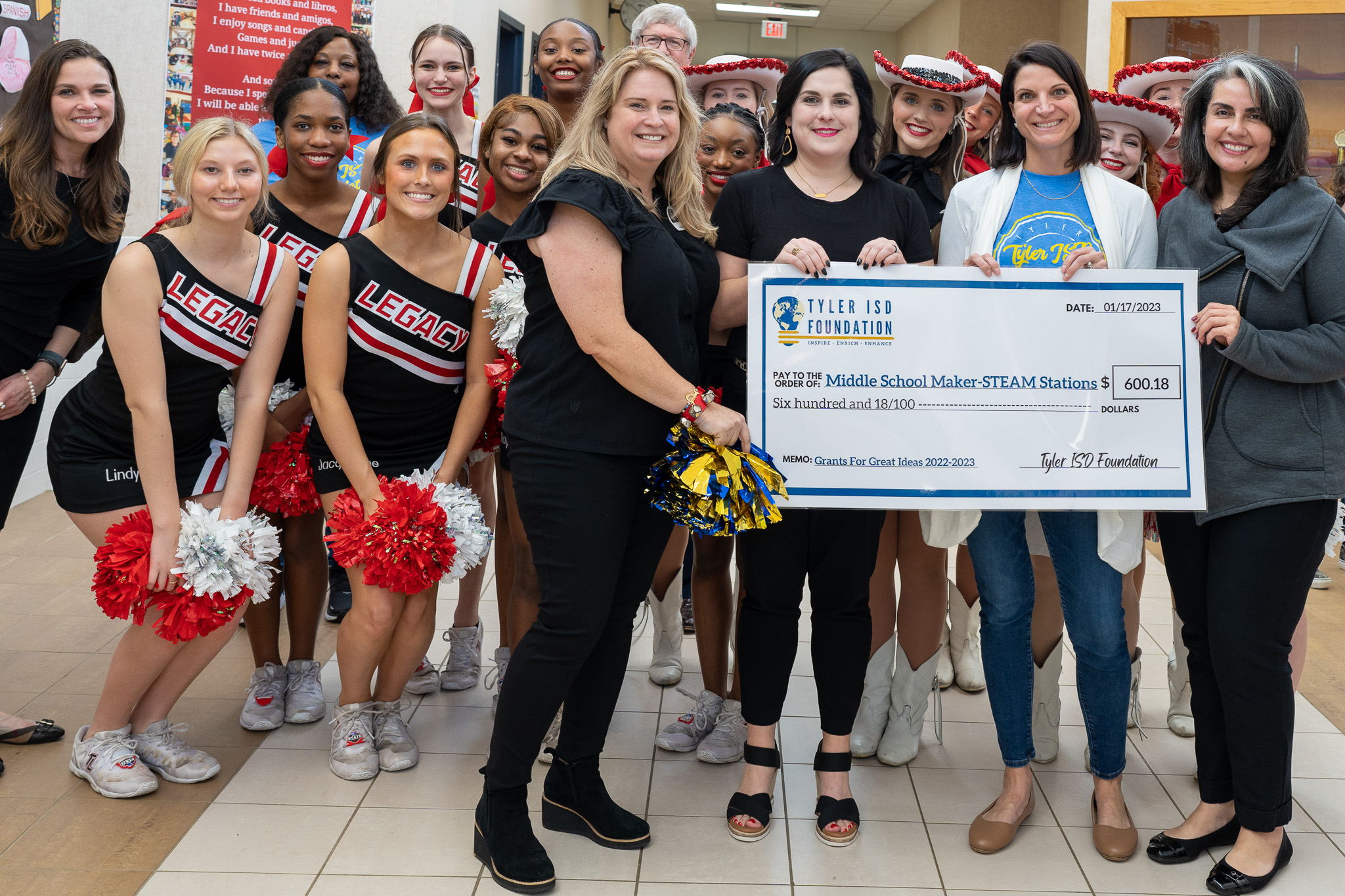 group of people standing in a hallway holding a giant check