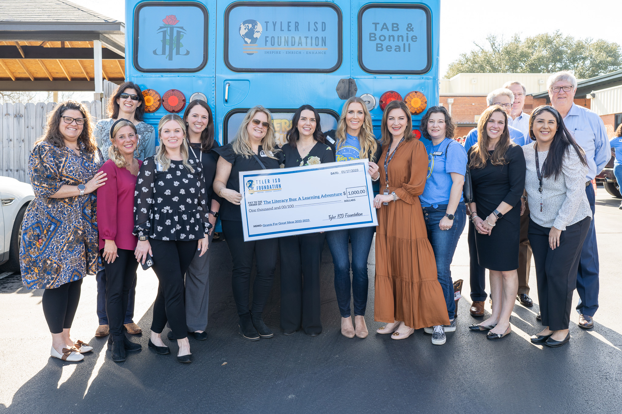 group of people standing in a hallway holding a giant check