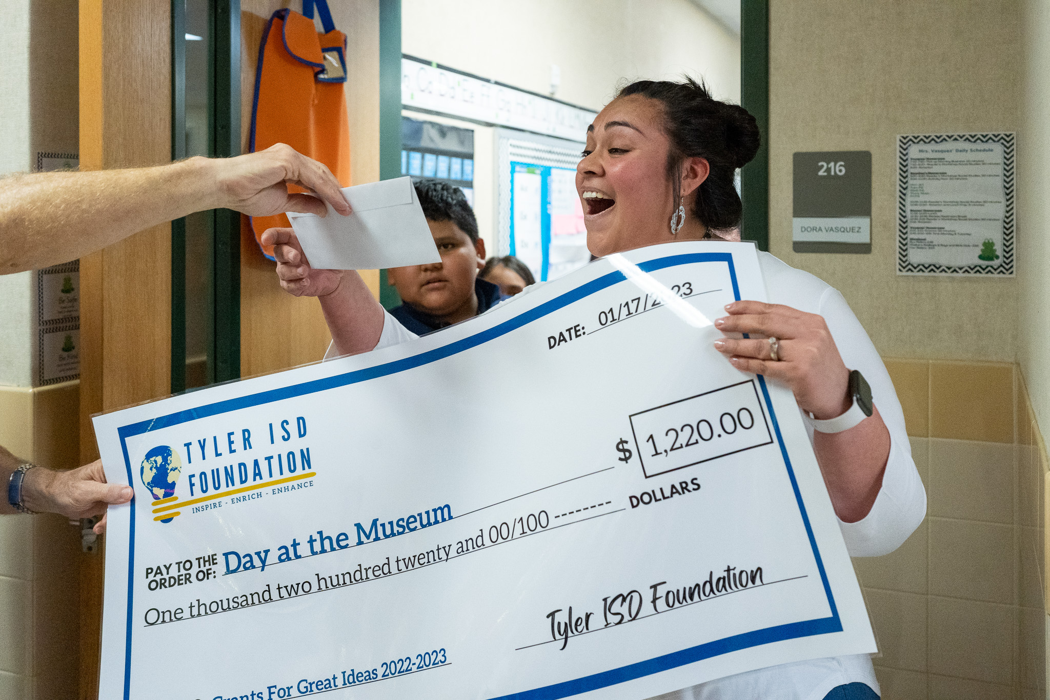 woman getting surprised with a giant check for a grant