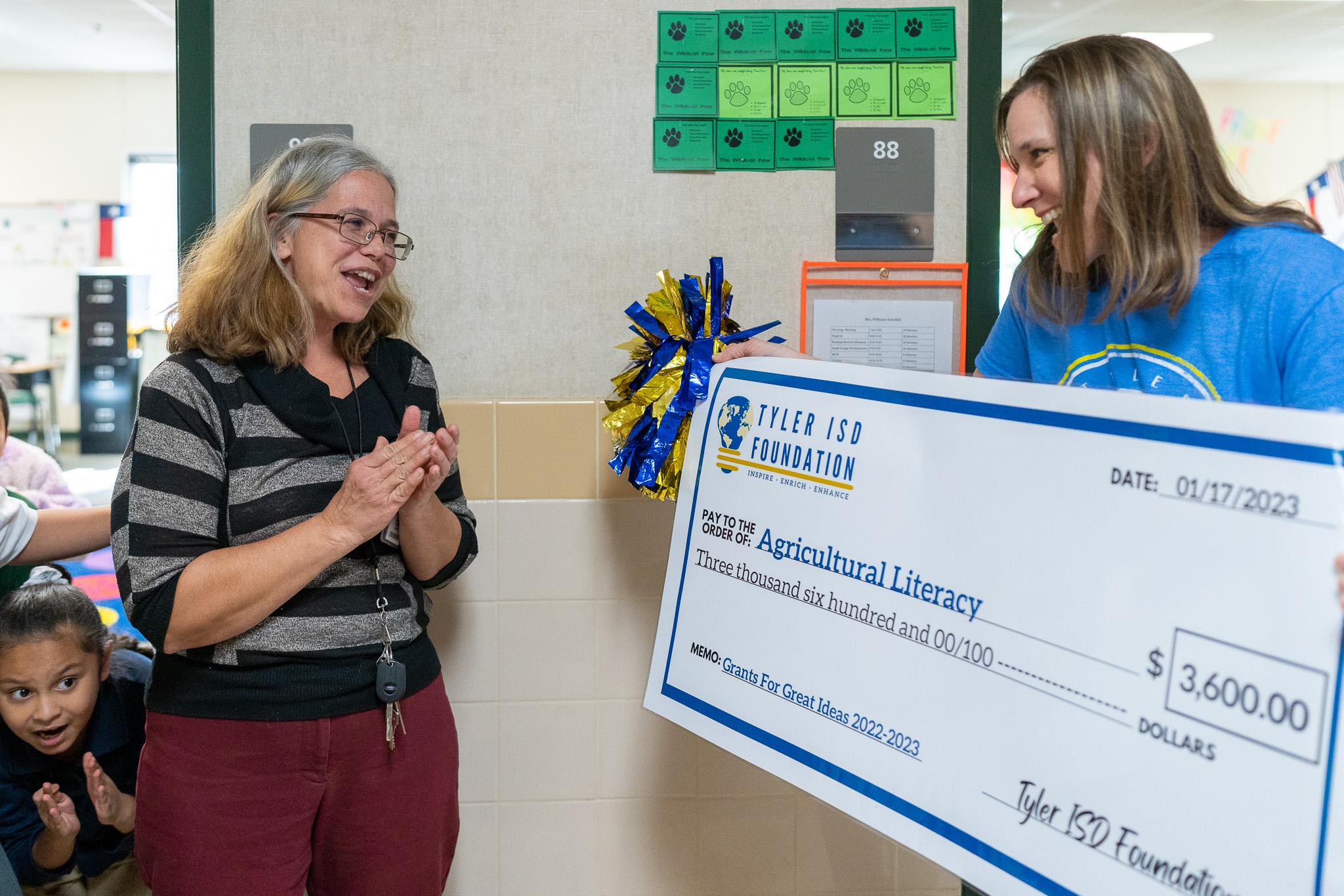 woman getting surprised with a giant check for a grant