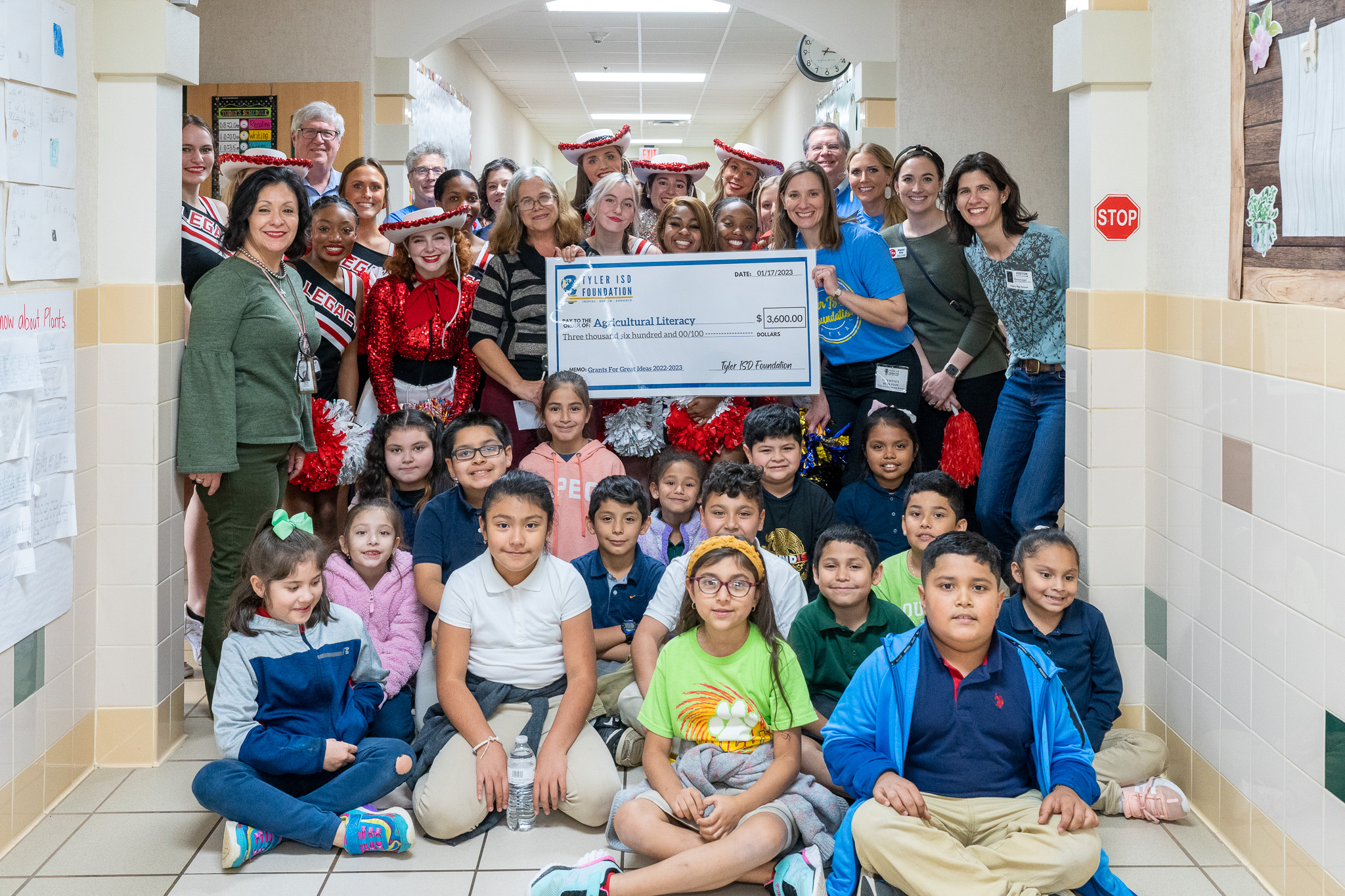 group of people standing in a hallway holding a giant check