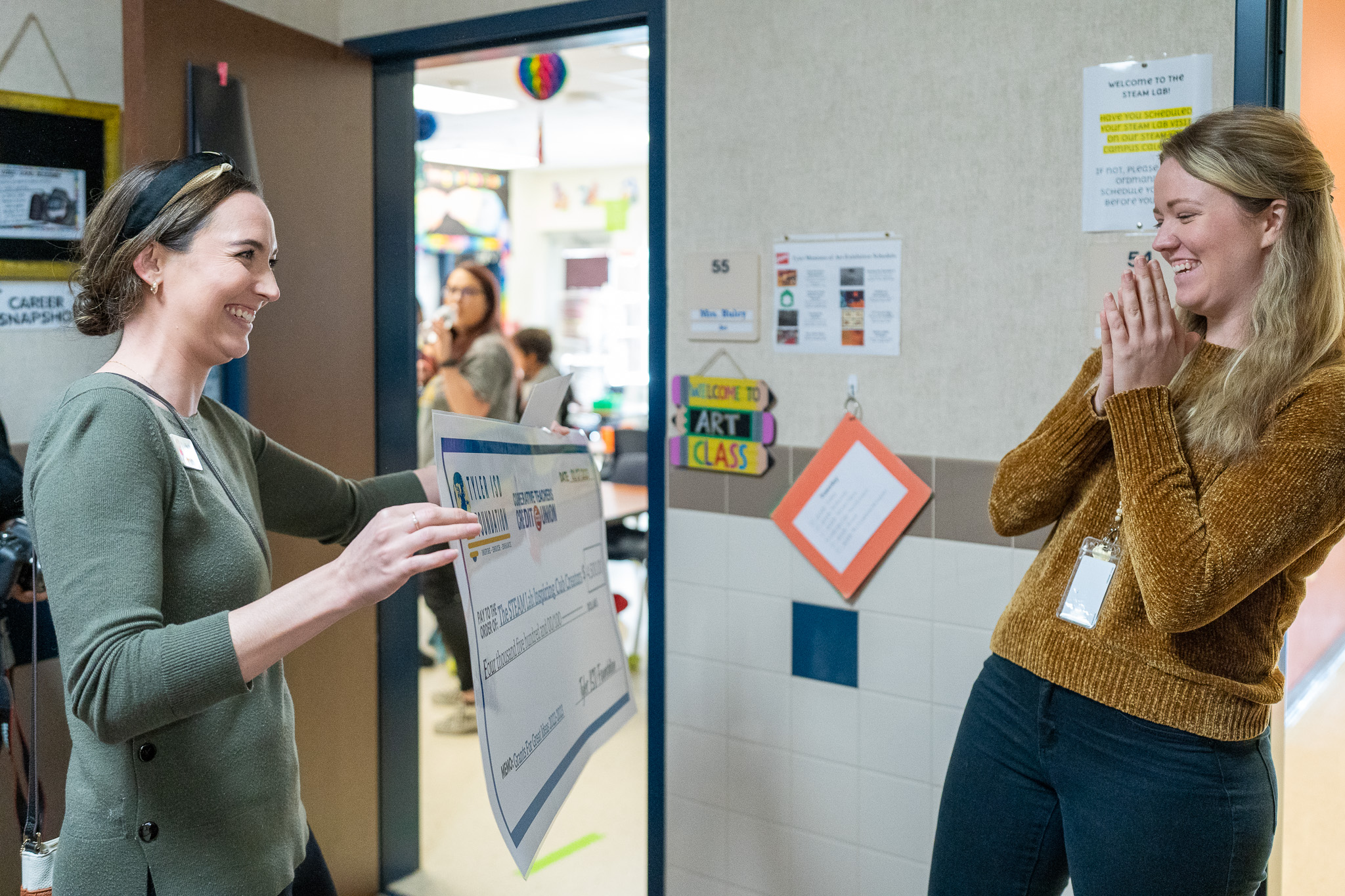 woman getting surprised with a giant check for a grant