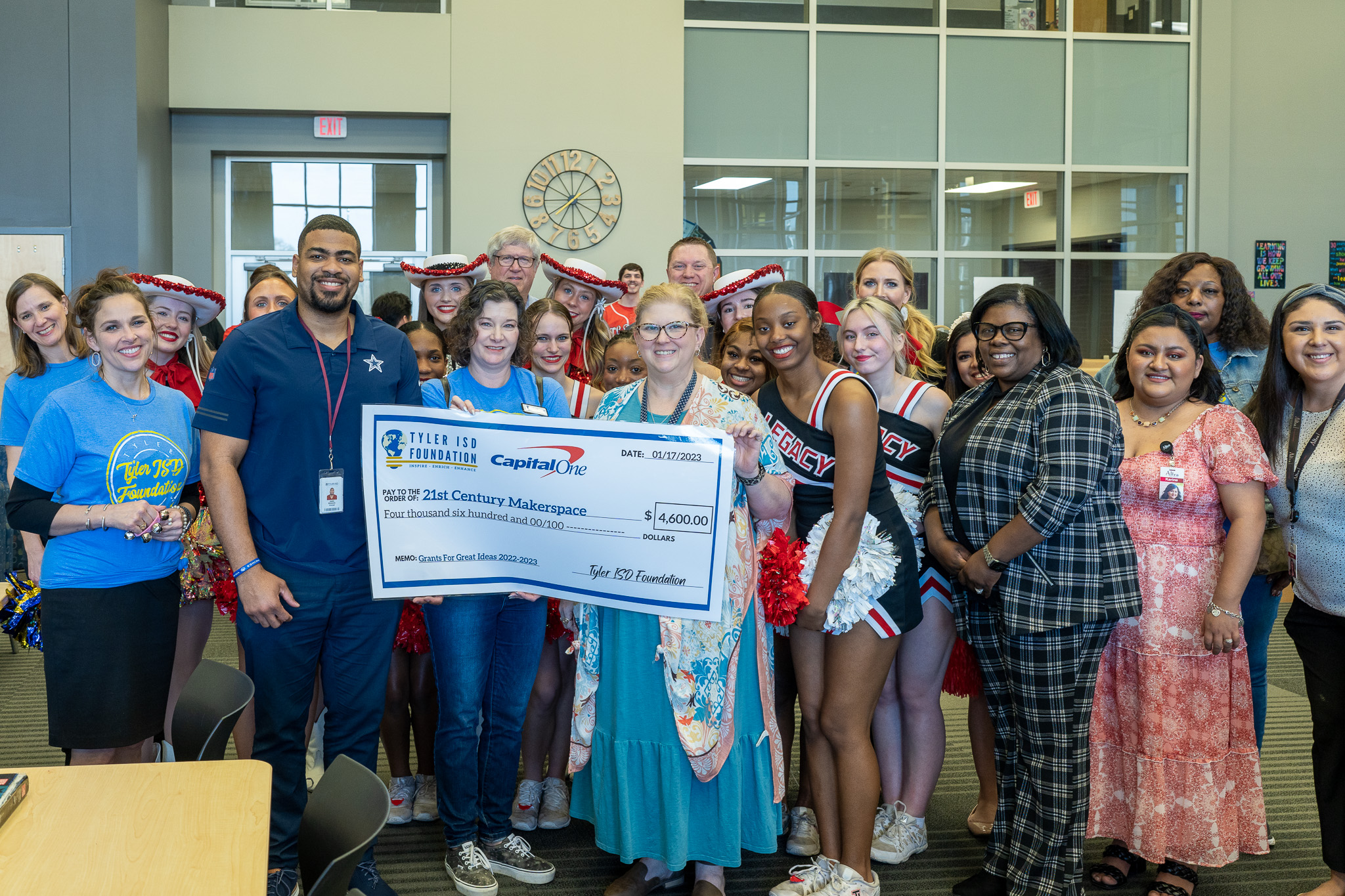 group of people standing in a hallway holding a giant check