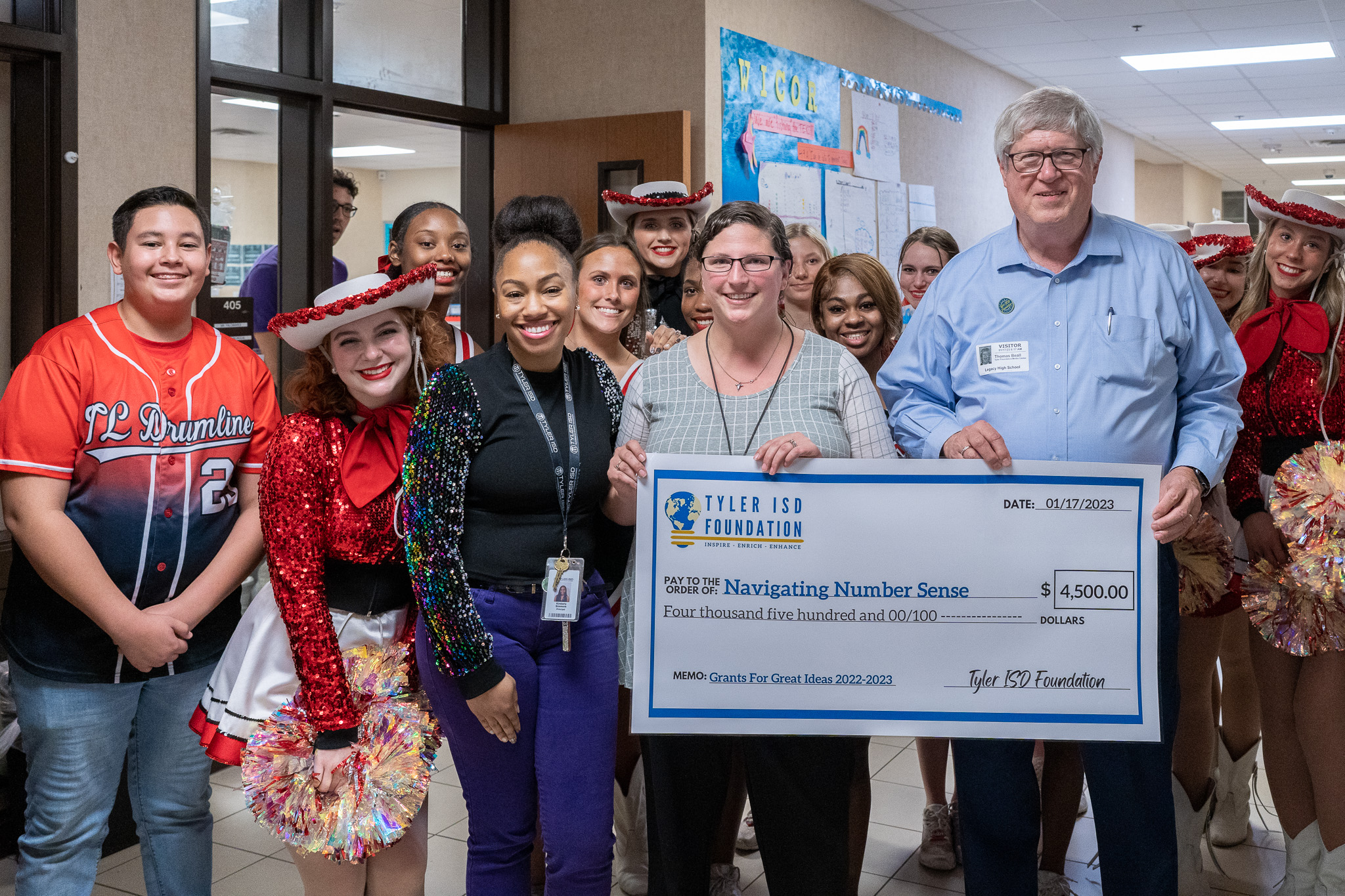 group of people standing in a hallway holding a giant check