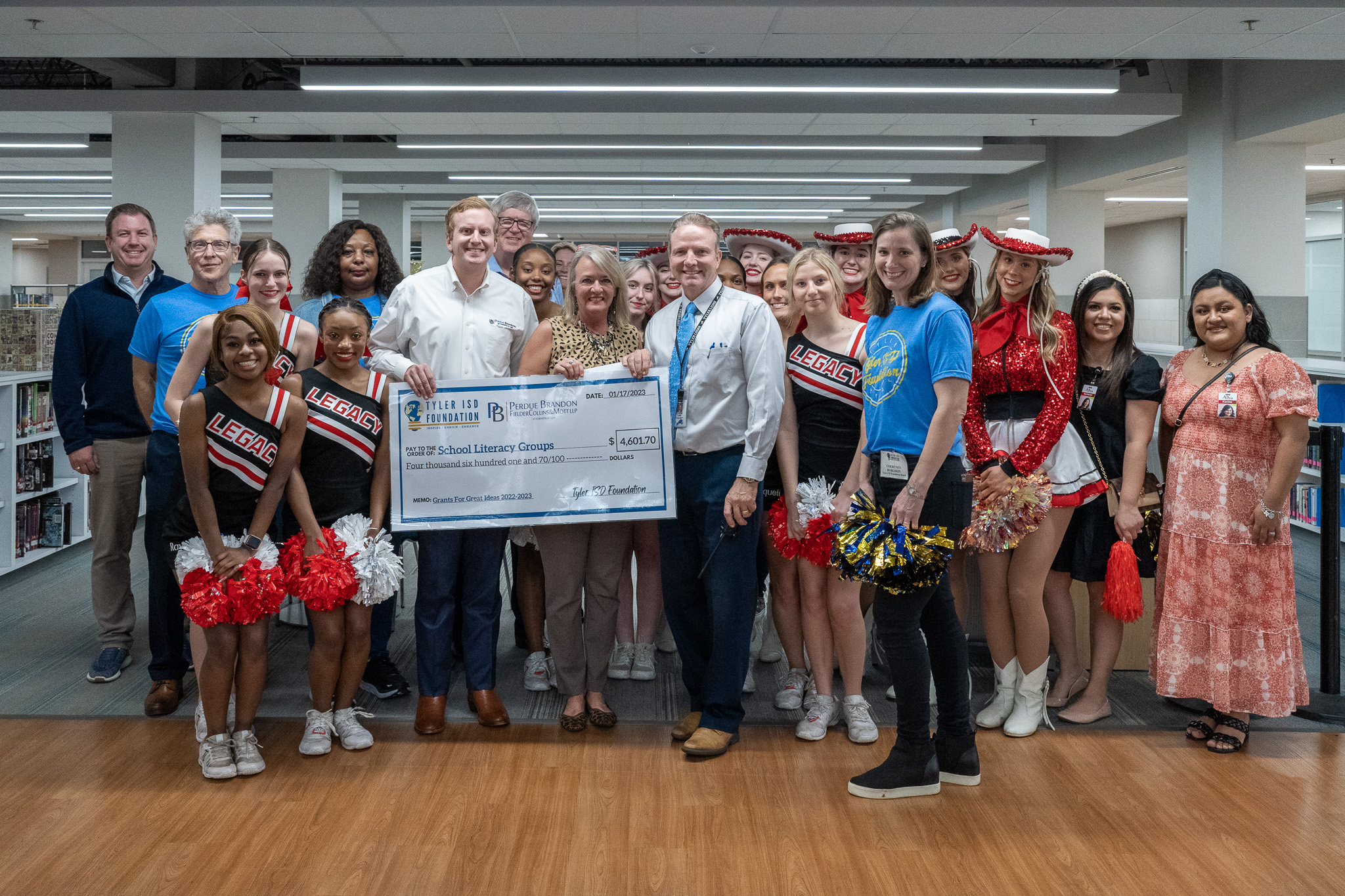 group of people standing in a hallway holding a giant check