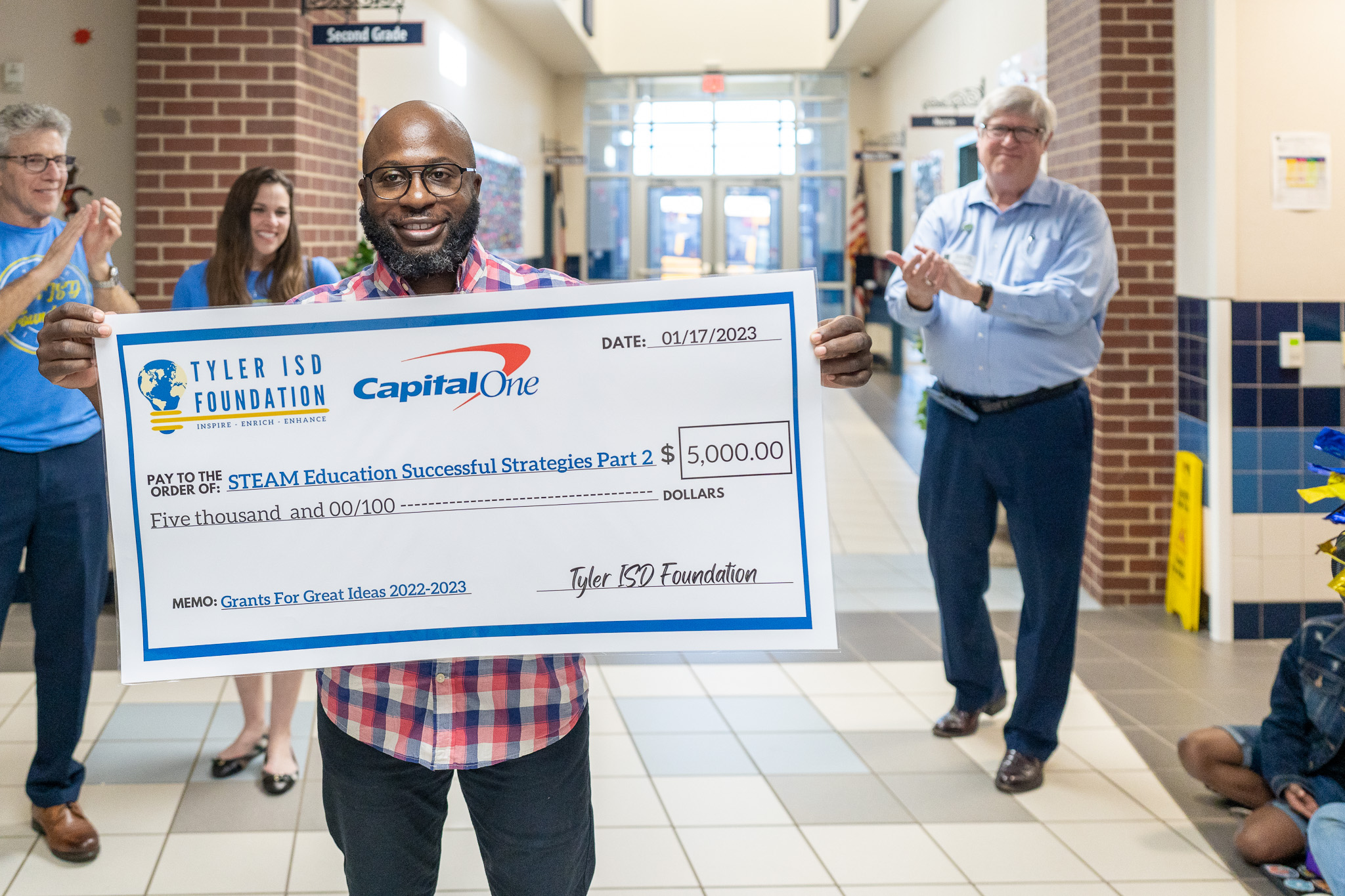 man getting surprised with a giant check for a grant