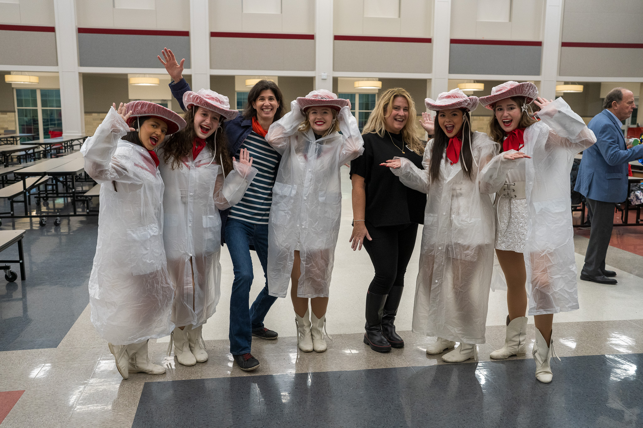 group of women in rain ponchos standing in a cafeteria