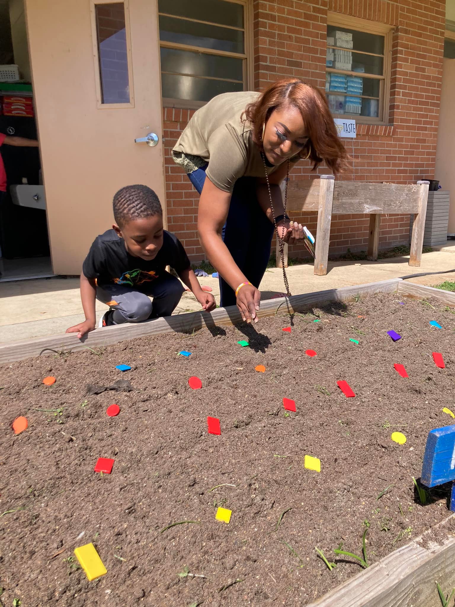 child and teacher planting sunflower seeds