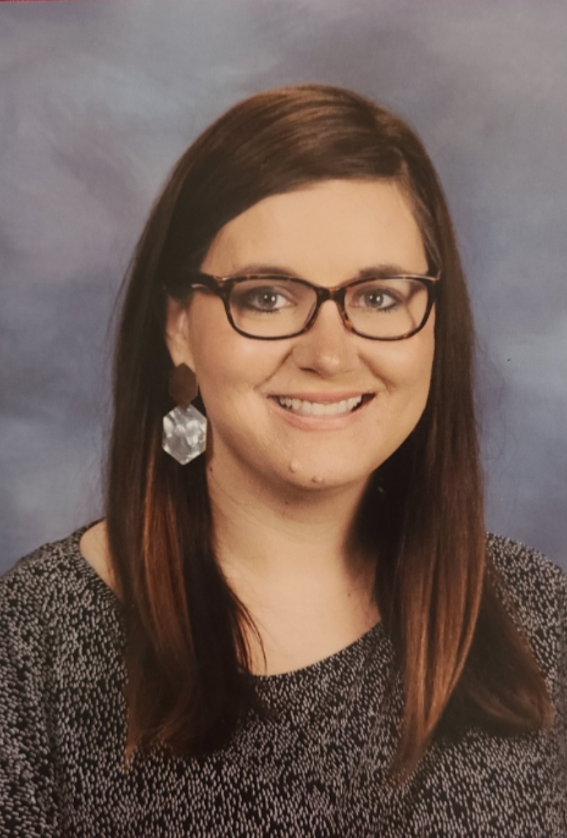 Caucasian Teacher with long brown hair, glasses, and big smile