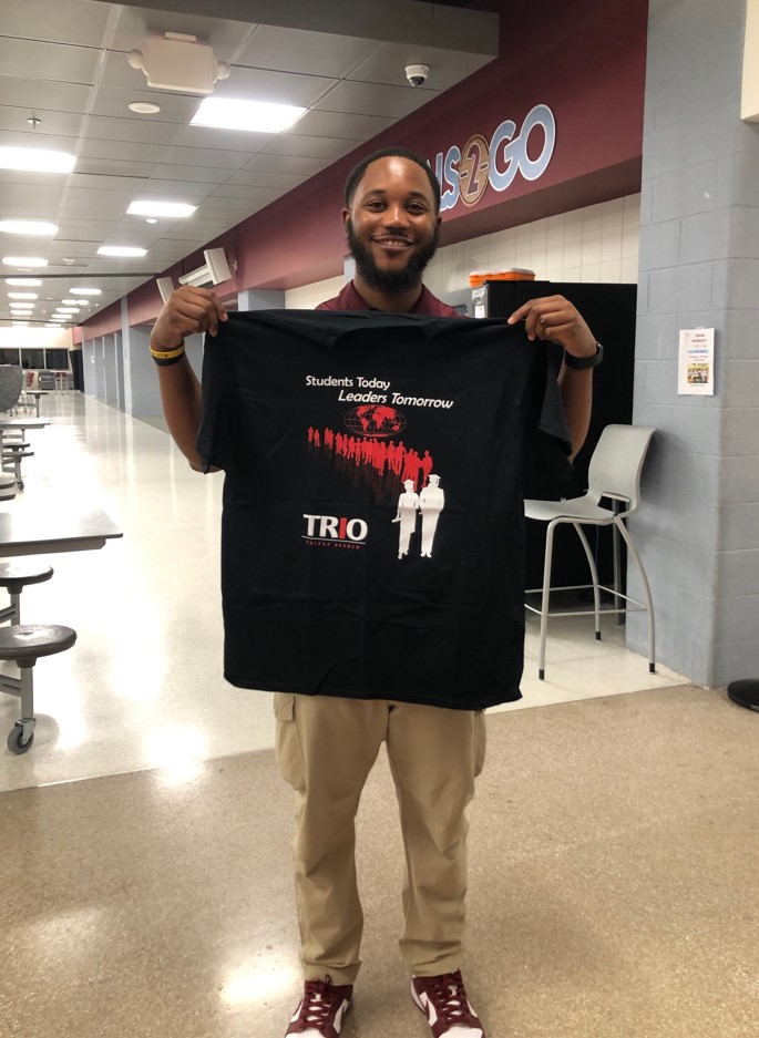 Picture of Jared Harris  holding  up a TRIO T-Shirt 