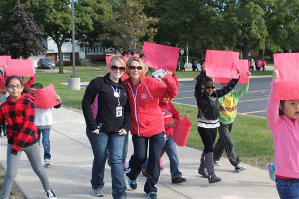 Students and adults walking with red signs
