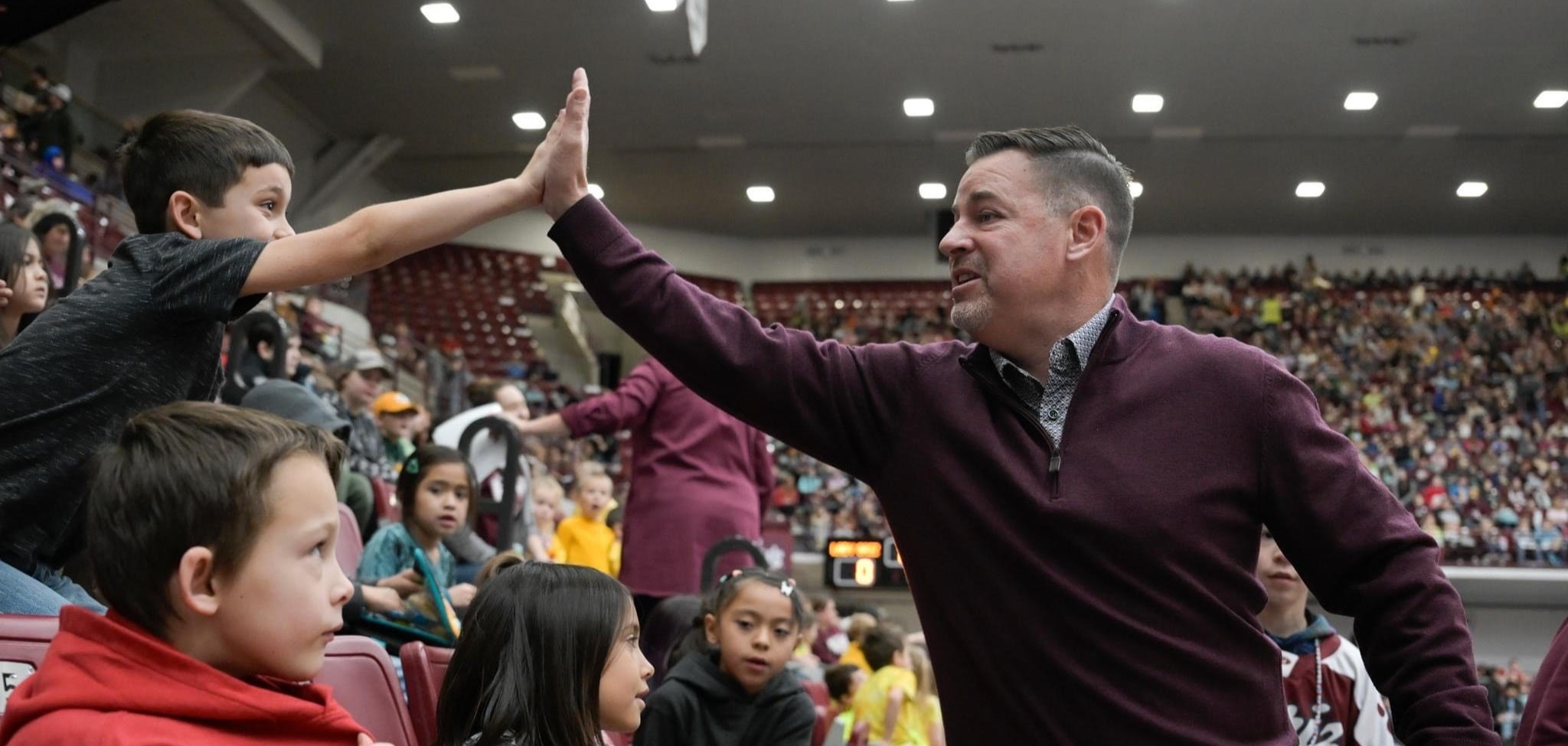 Eddy high fives the Lady Griz Coach on his 50th game win as his classmates look on.