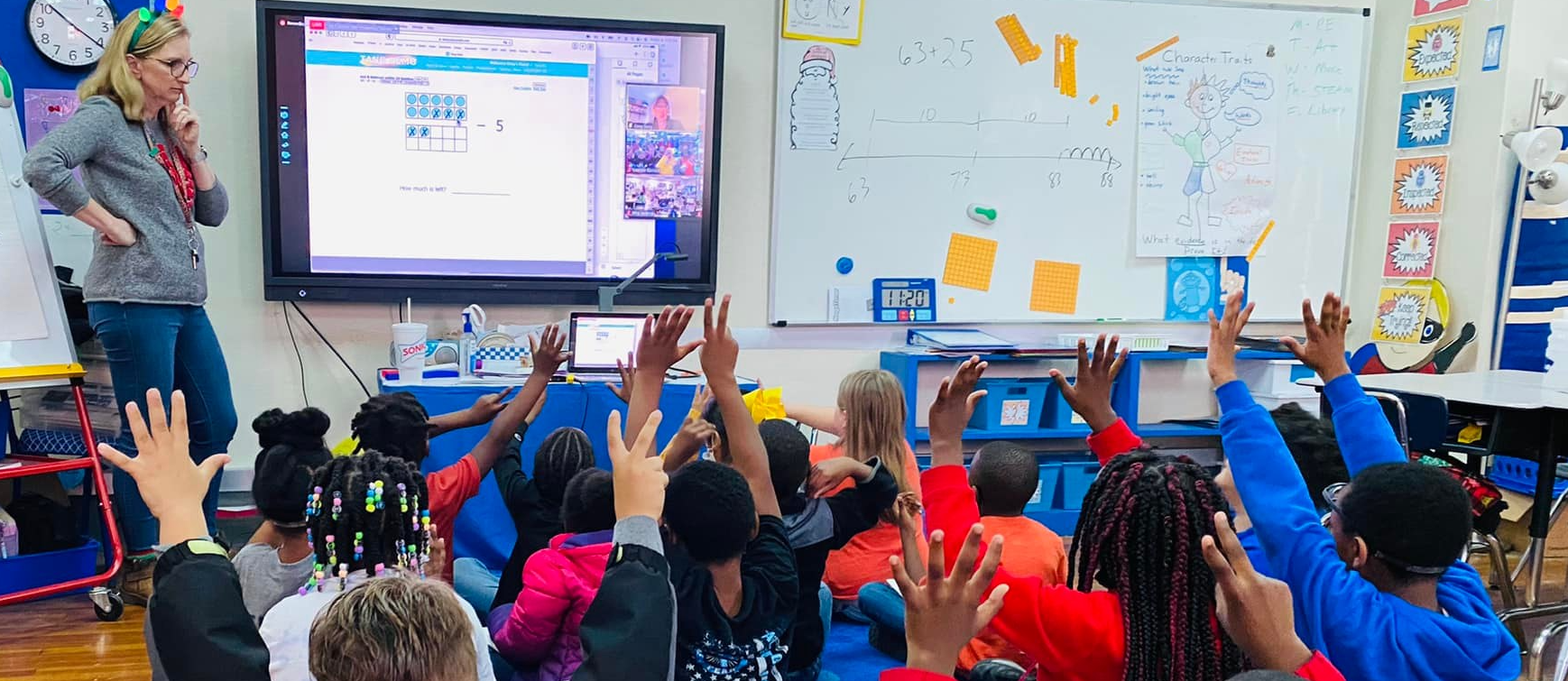 Students raise hands to answer a question during a math lesson.