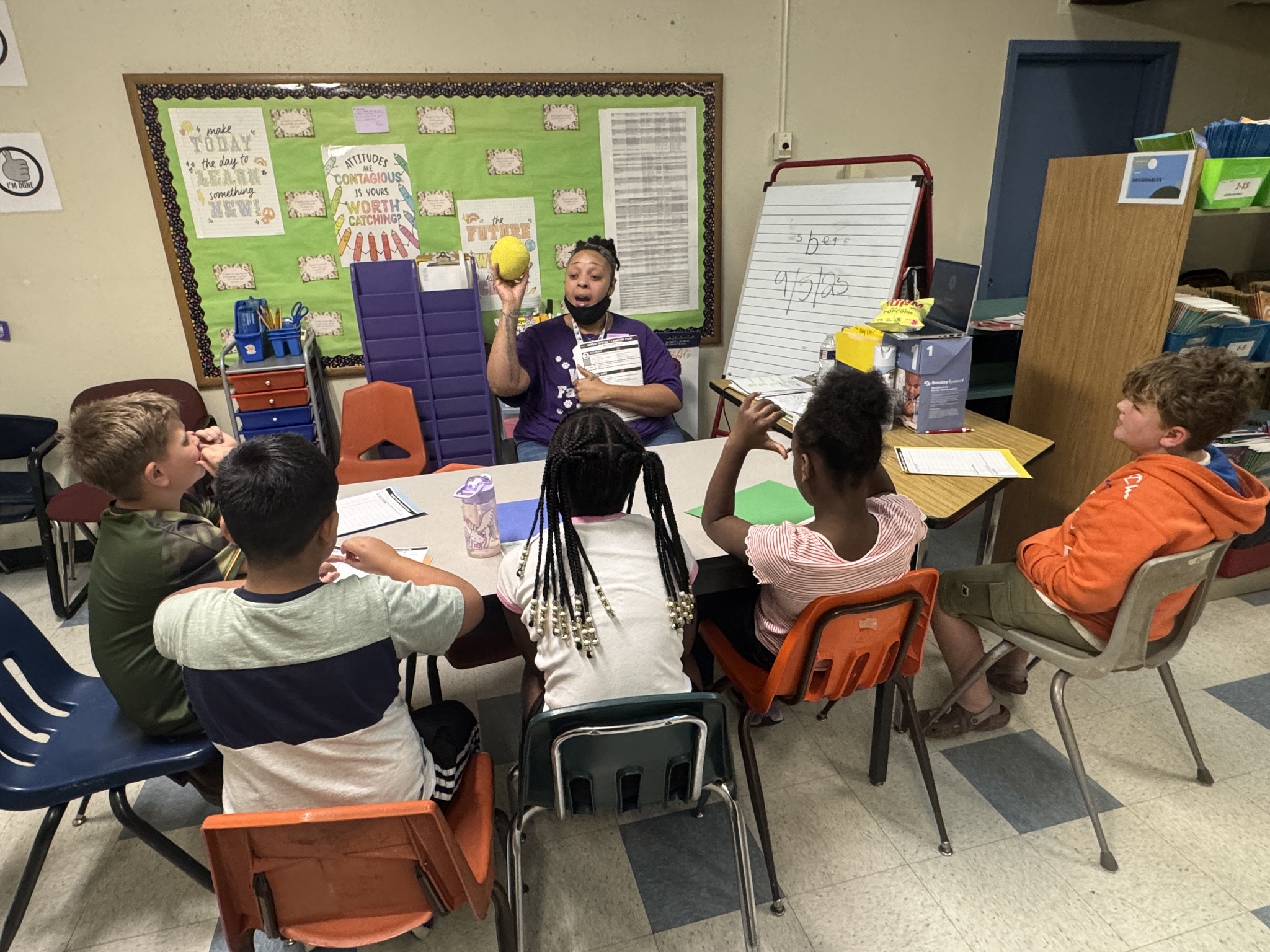 students around a small group table learning from a para