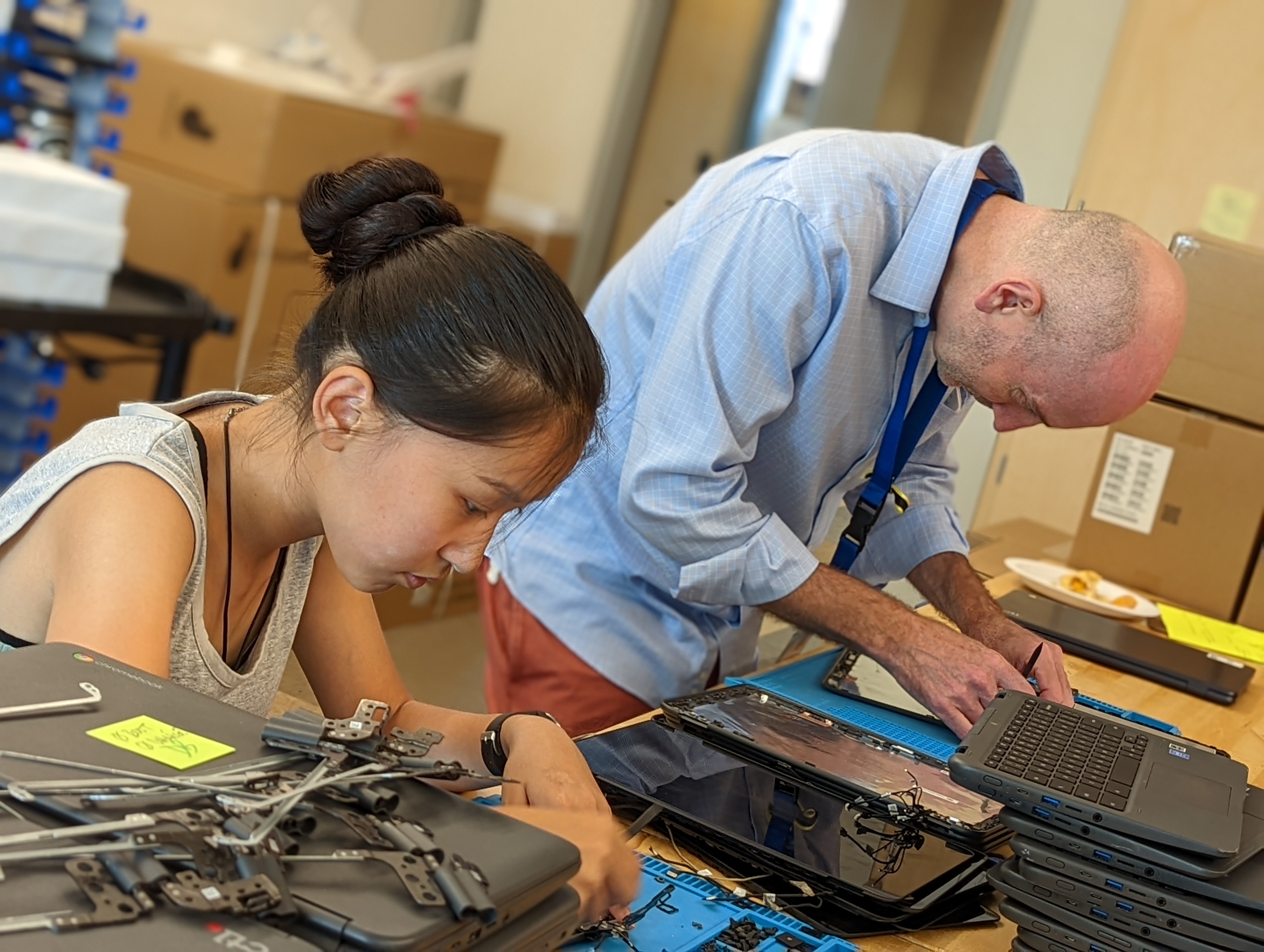 A female student and male employee are pictured repairing chromebook computers.