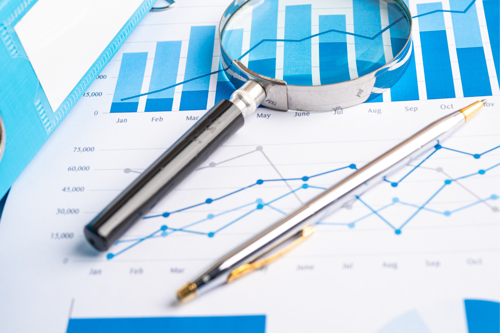 picture showing magnifying glass and pen sitting on top of a chart
