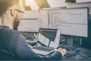 a man works on multiple computer screens