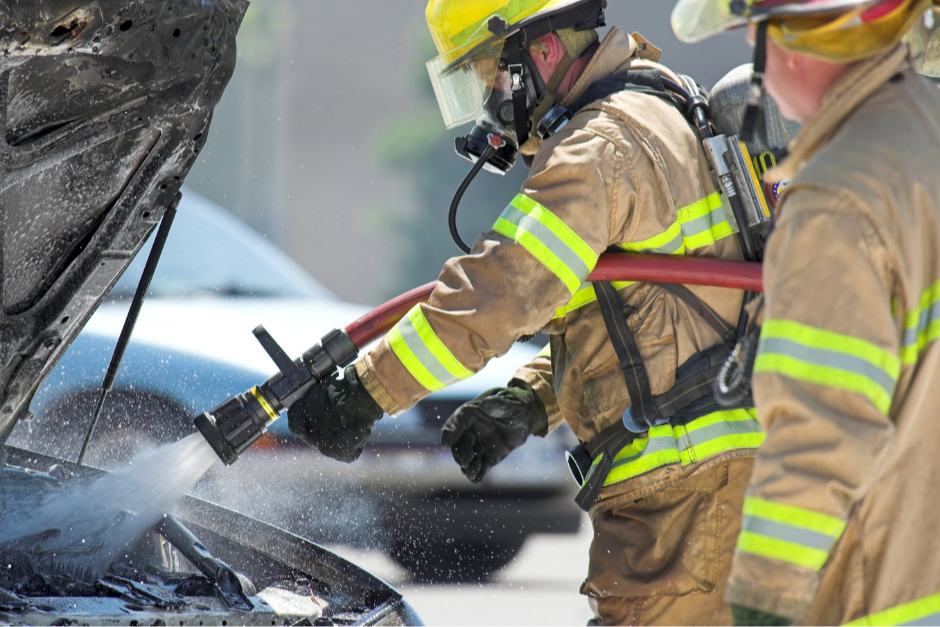 a firefighter puts water on a car engine