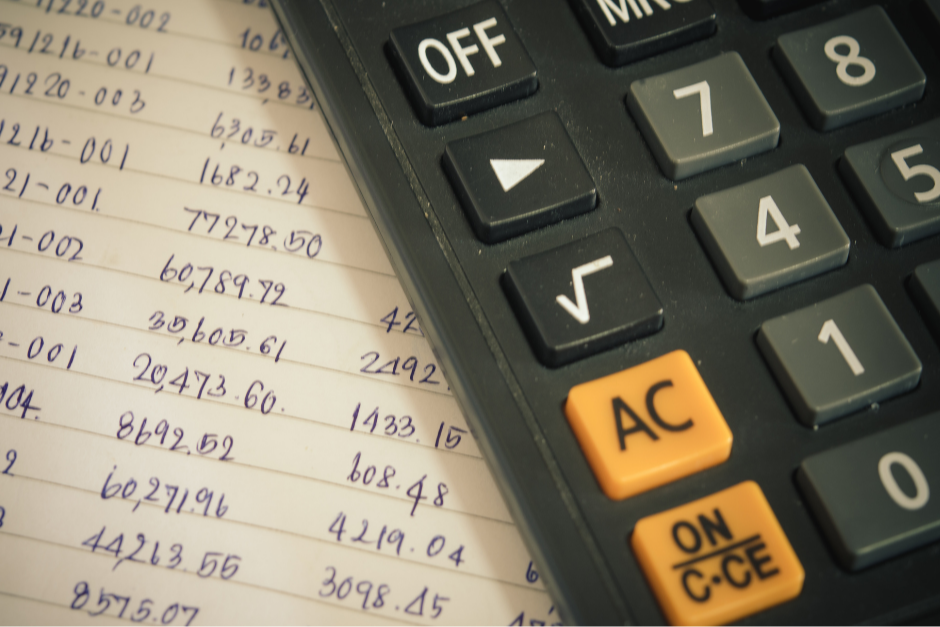 a close up image of a calculator sitting on top of a handwritten page of numbers in columns