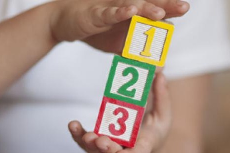 A child holds a stack of colorful blocks numbered 1, 2, and 3 in their hands.