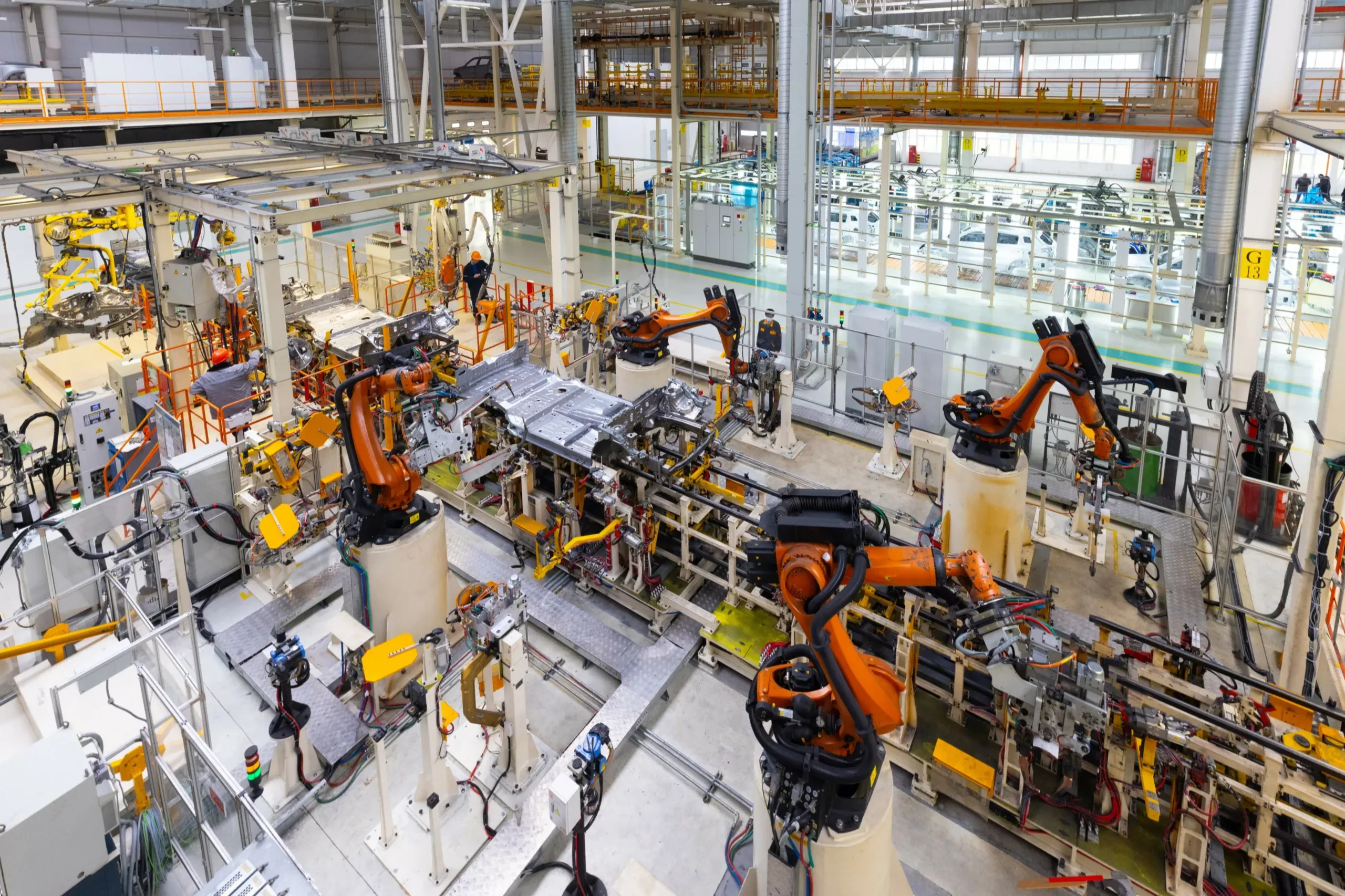 A large industrial setting with numerous robotic arms performing assembly tasks on vehicles within a factory environment.