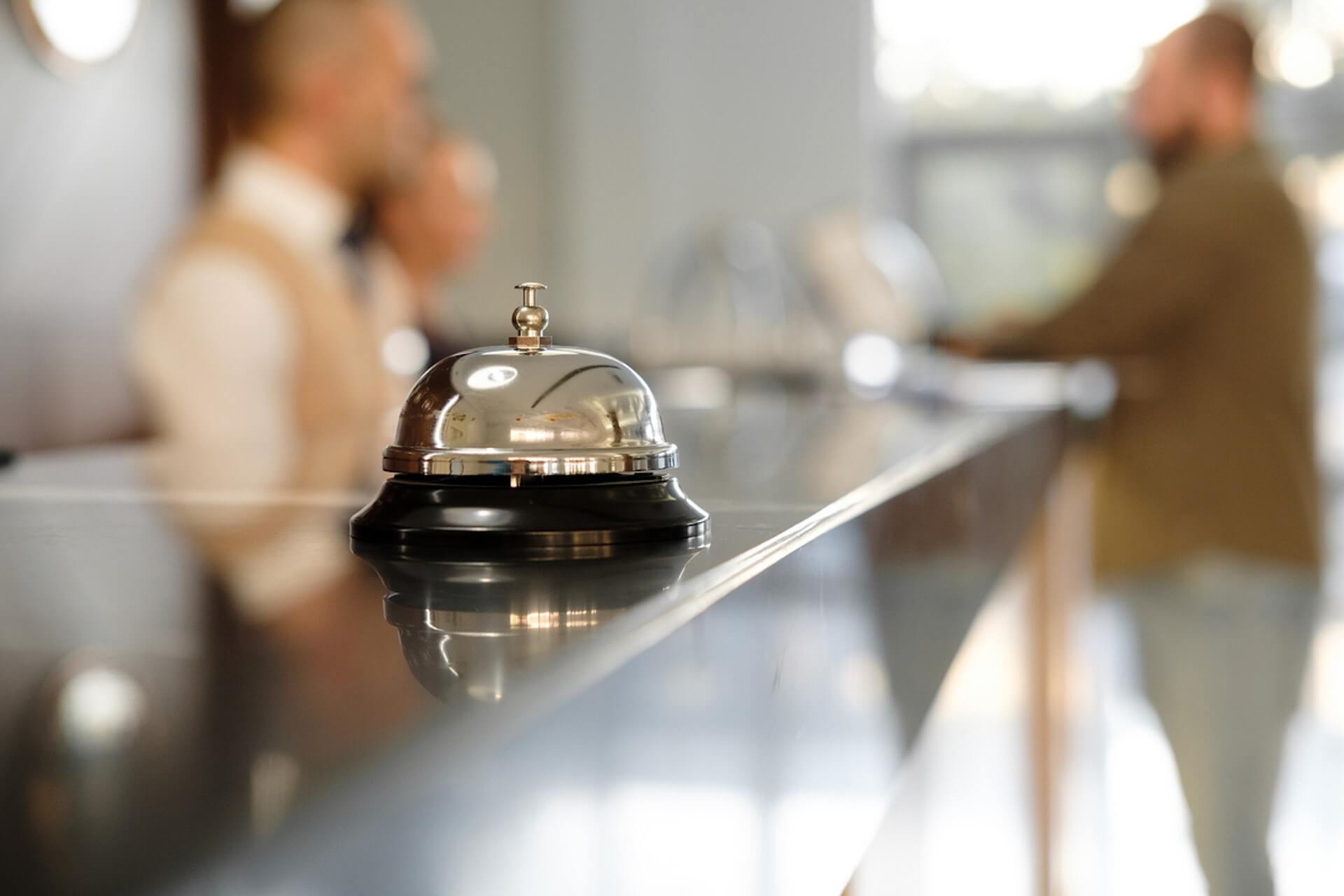 Bell on a reception desk with blurred people in the background.