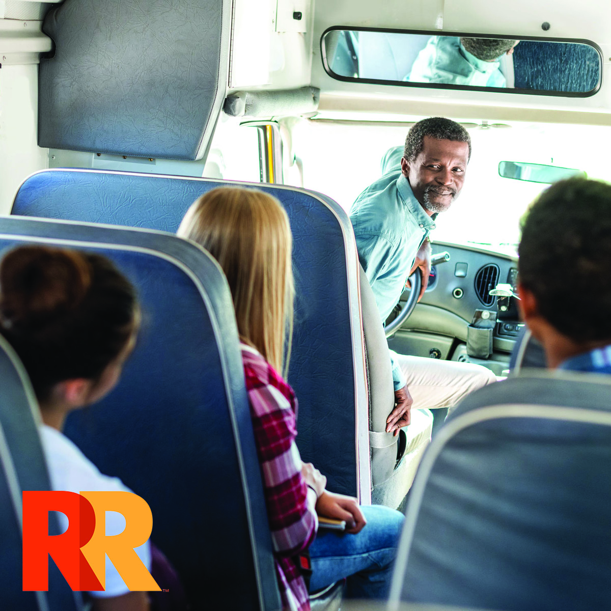 Bus driver turning around to talk to students while bus is parked