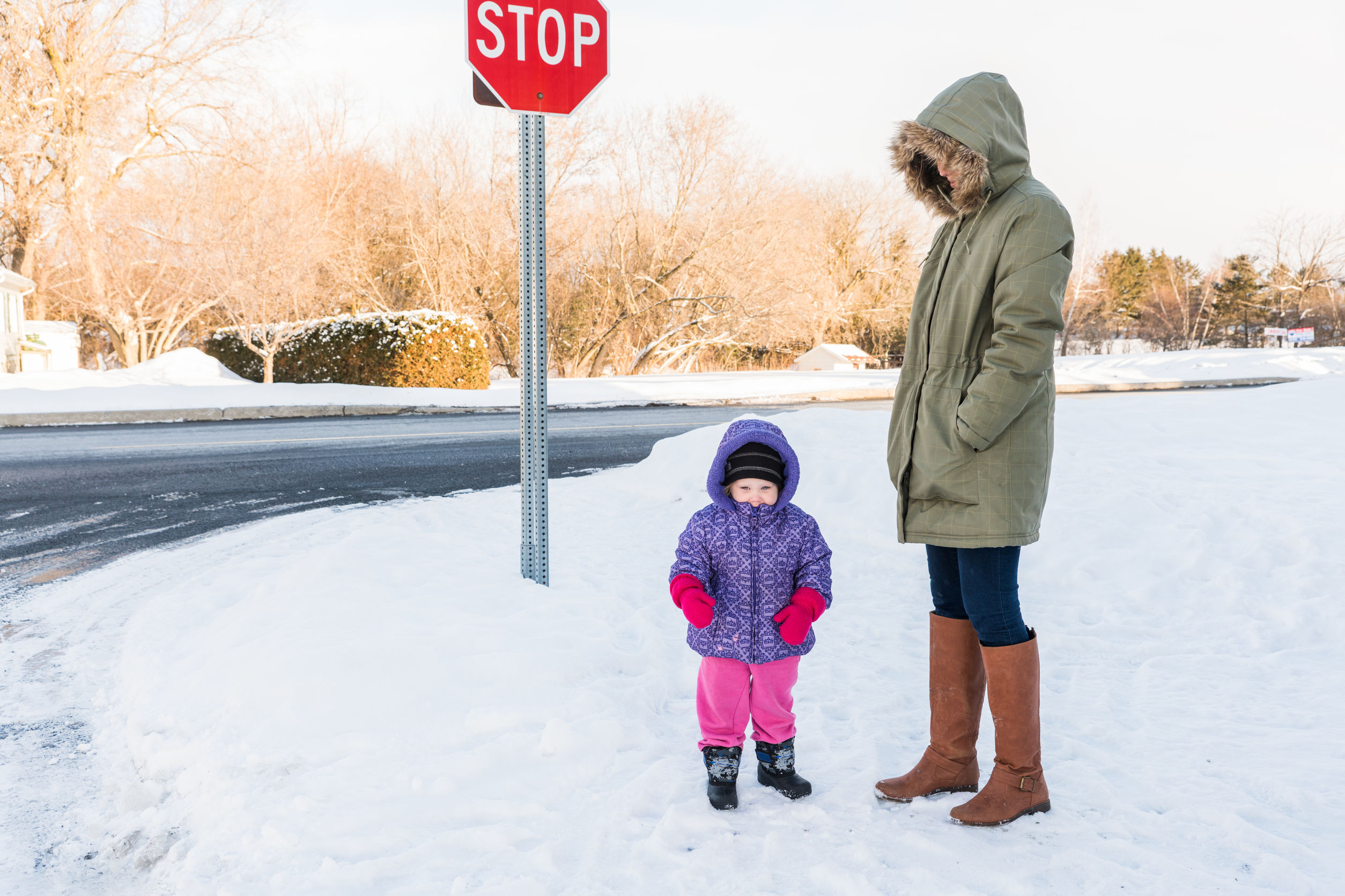 Child and parent in snow standing by a stop sign