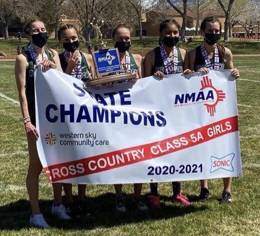 Photo of championship women's cross country team for 20-21 School year. They are holding a banner.