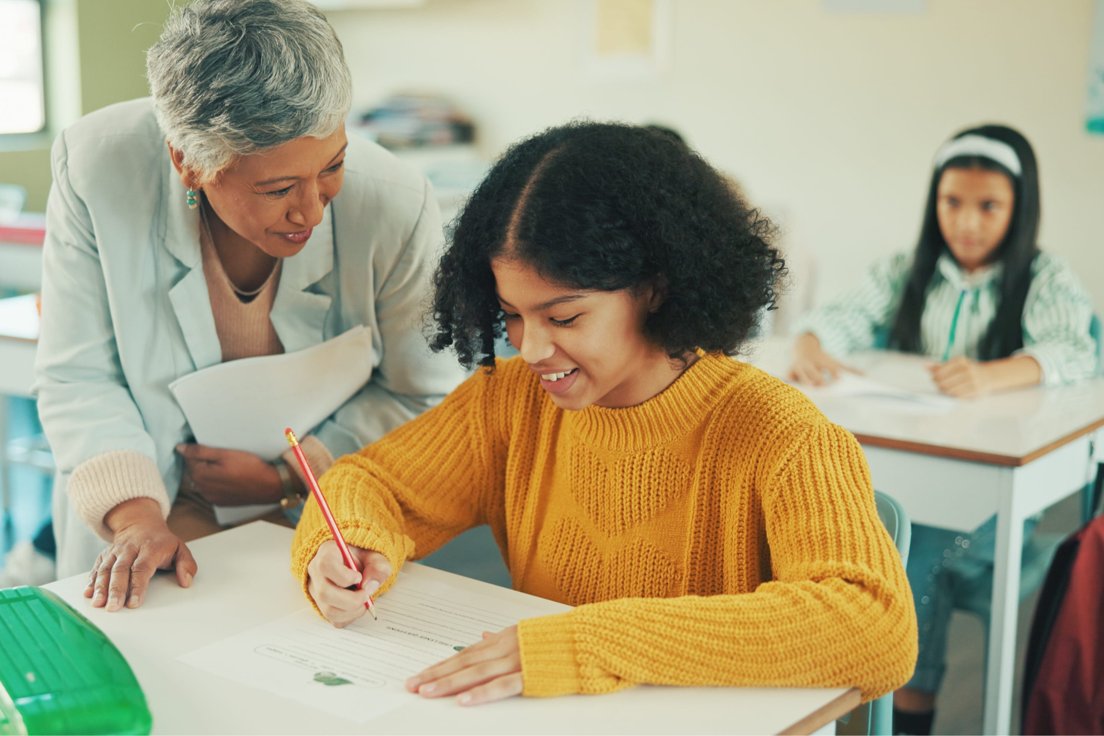 teacher helping 2 students in classroom