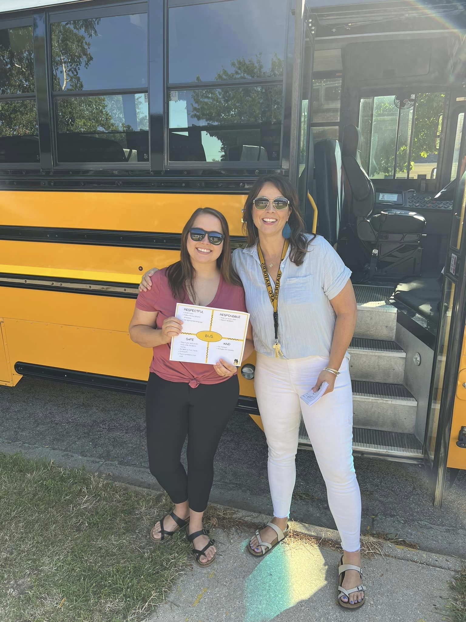 Two AFC staff members standing next to yellow school bus