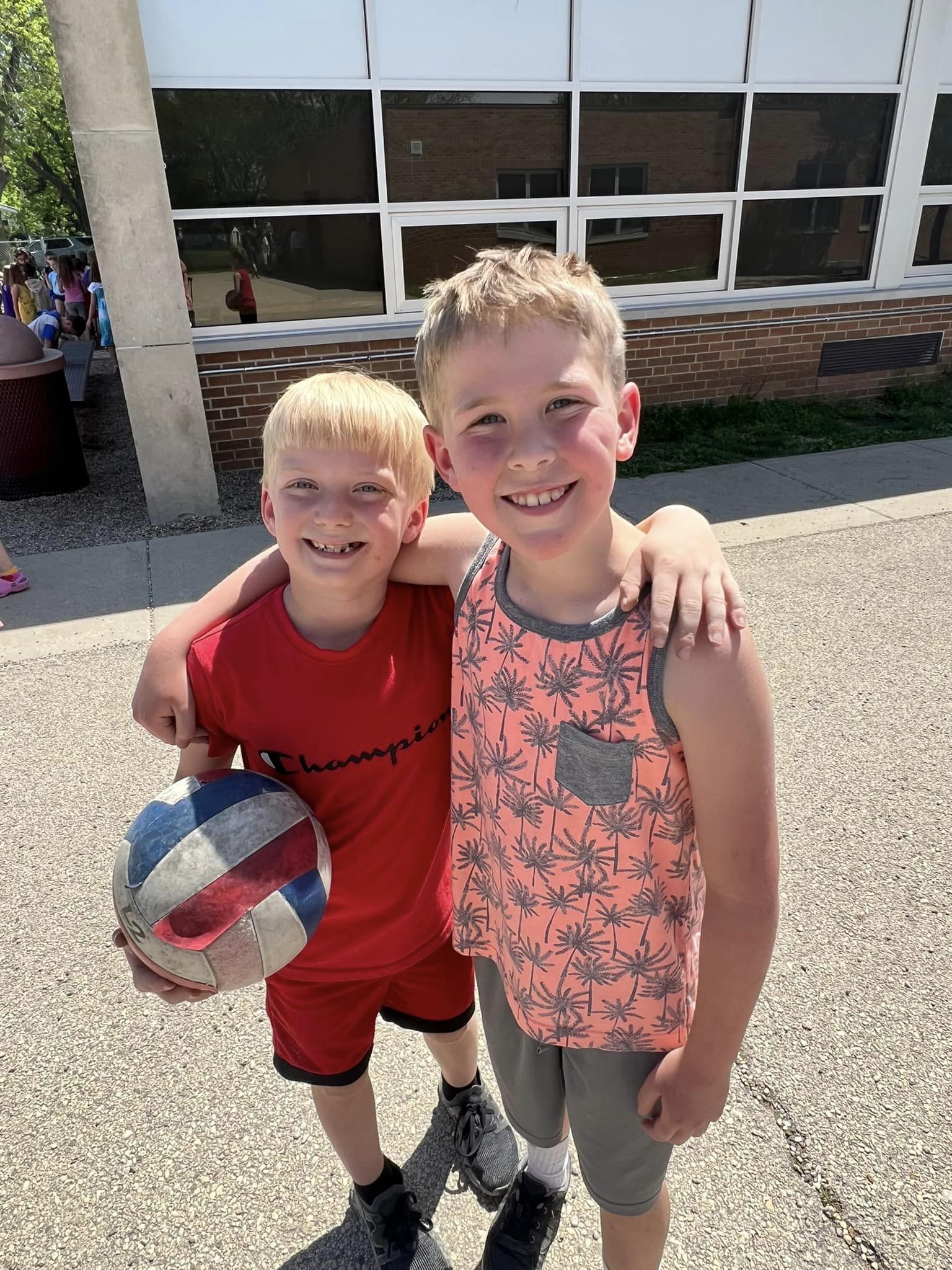 Two boys smiling at recess, one holding ball