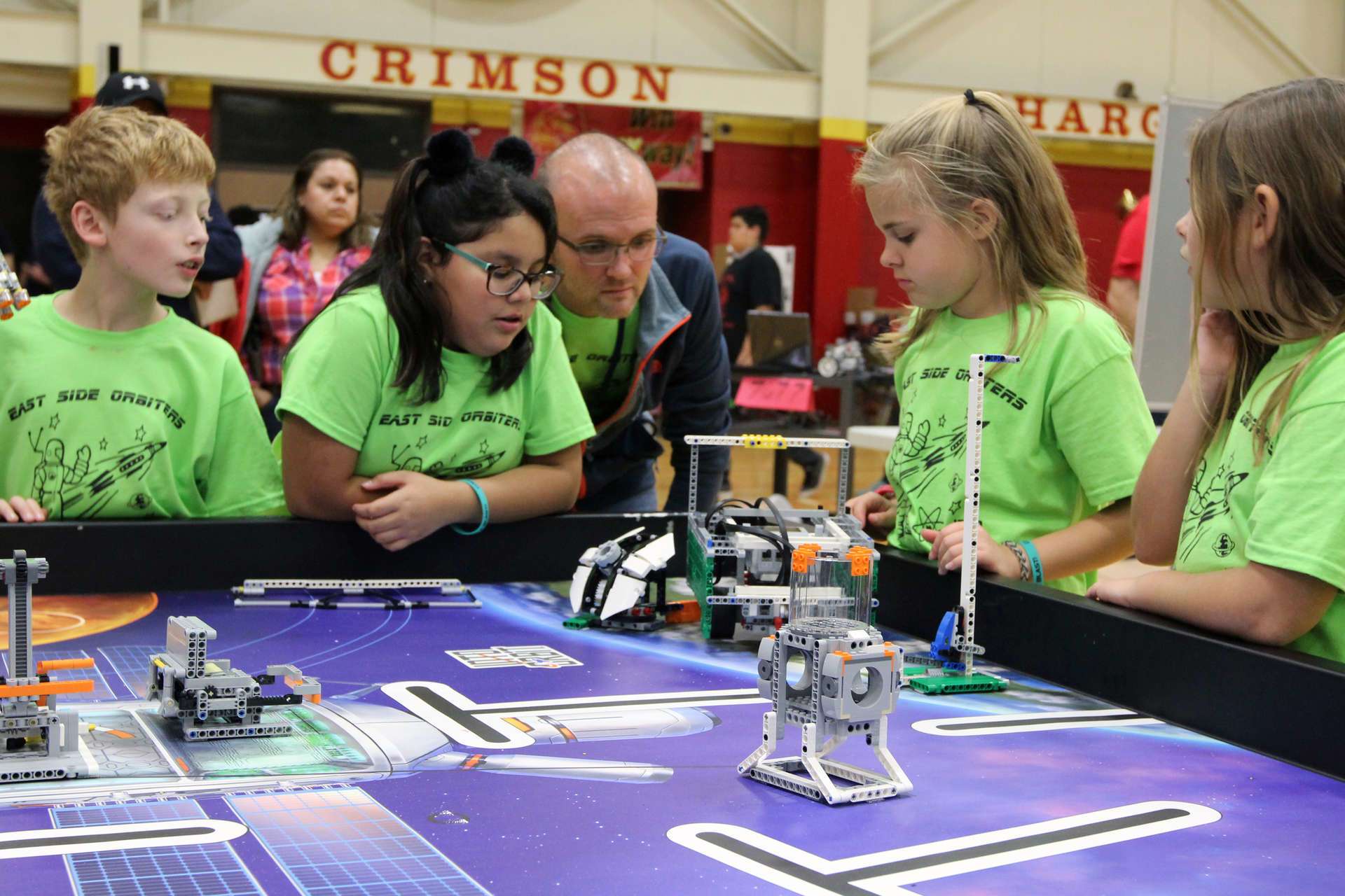 Staff member and students looking at small robots on a table