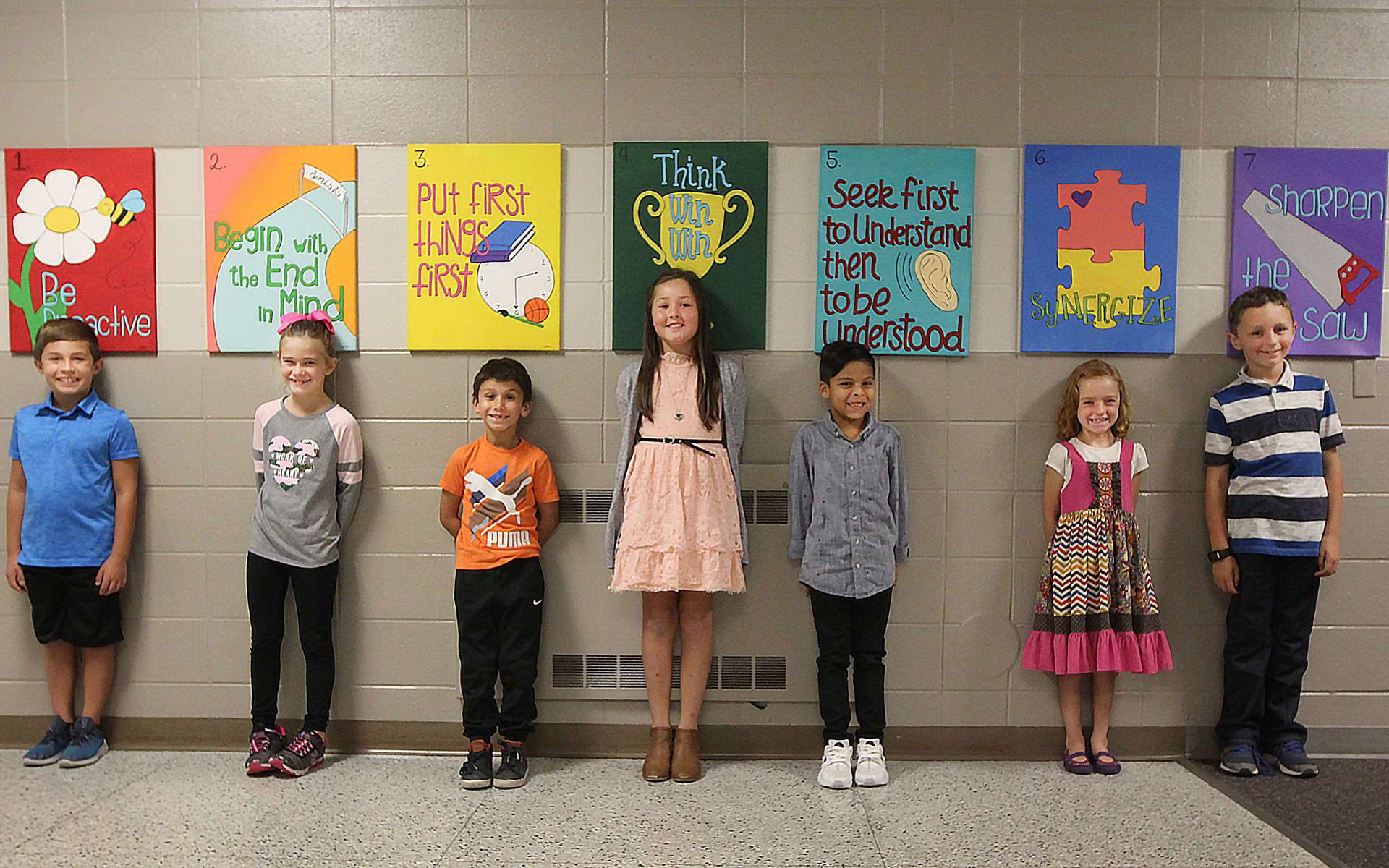 Several students standing under their individual art projects