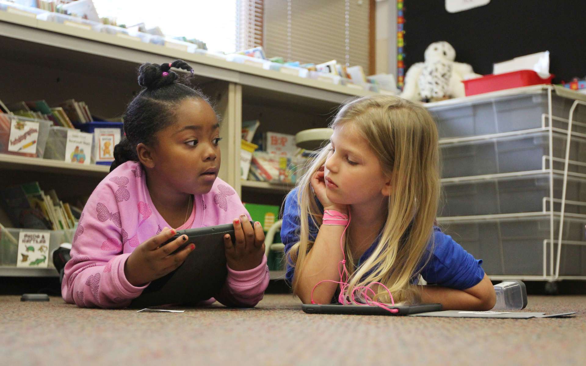 Two students laying on the floor talking to each other