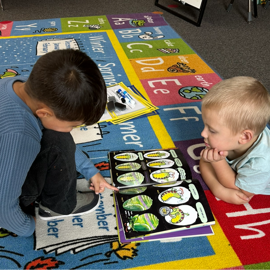 Two students reading a children's picture book together. 