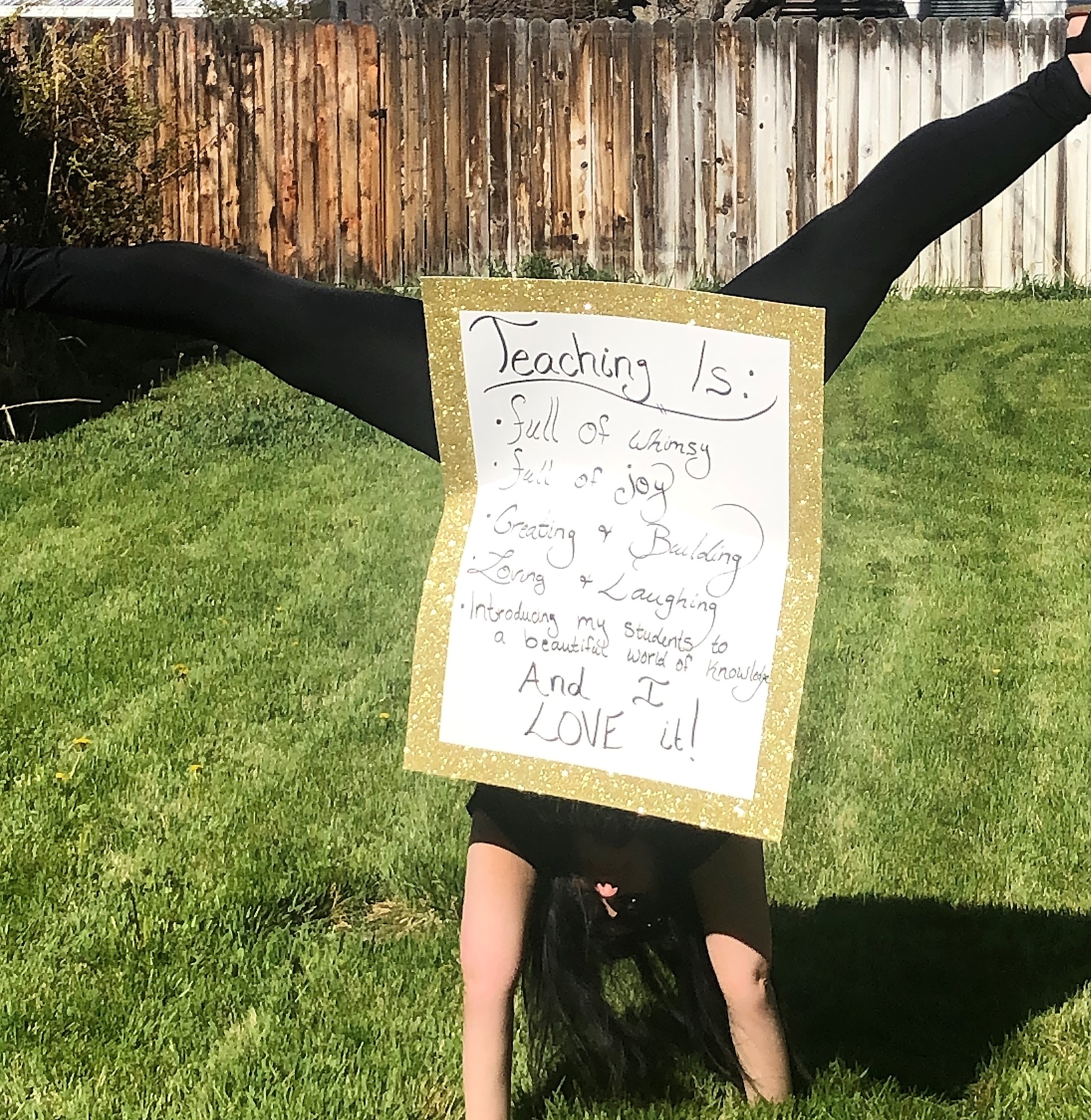 person doing a handstand with a sign that reads: Teaching is: Full of Whimsy   Full of Joy  Creating & Building  Loving & Laughing  Introducing my students to a beautiful world of knowledge 