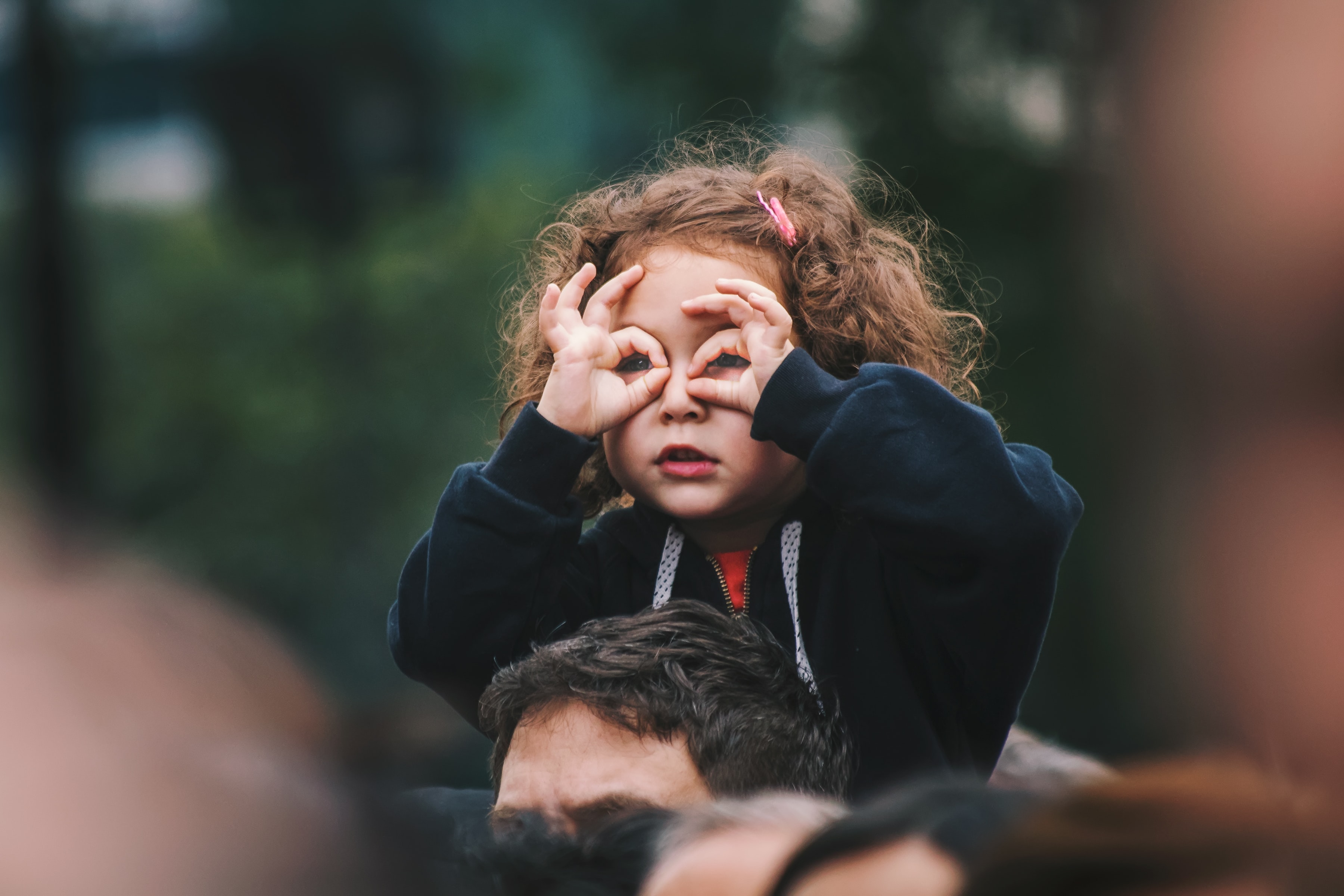 girl on shoulders looking through hands