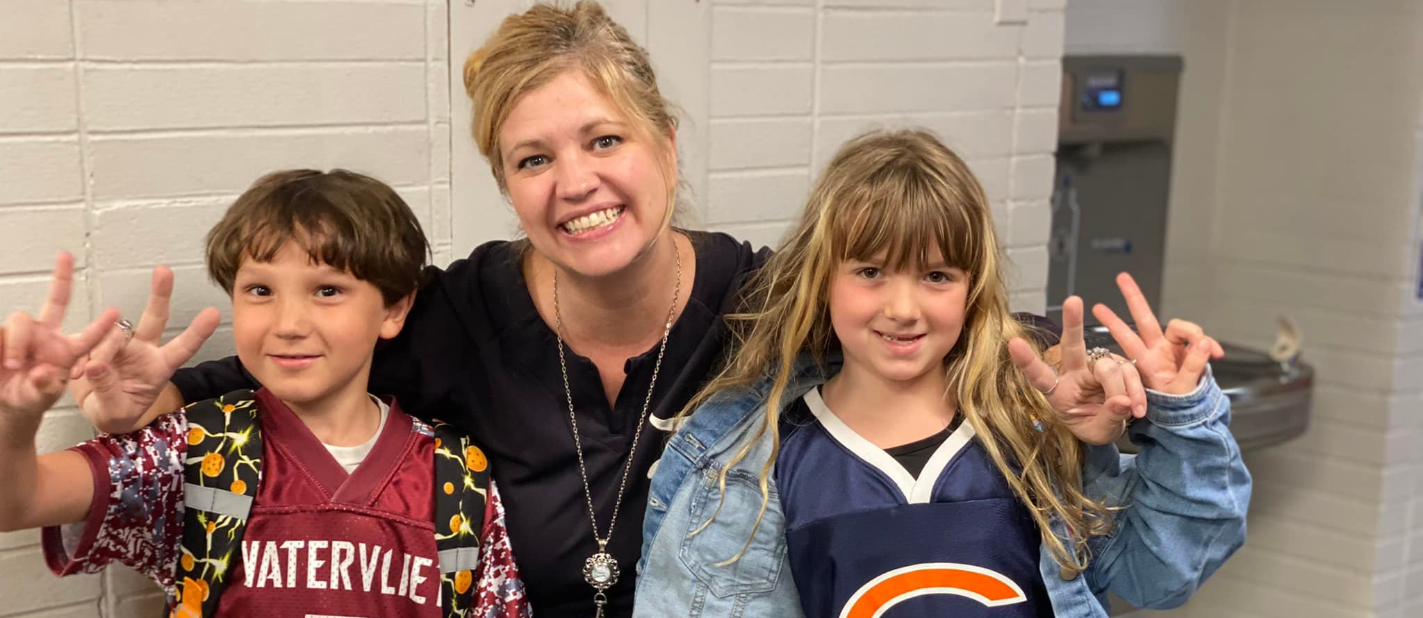A teacher with a boy and girl student on Jersey Day, wearing team jerseys