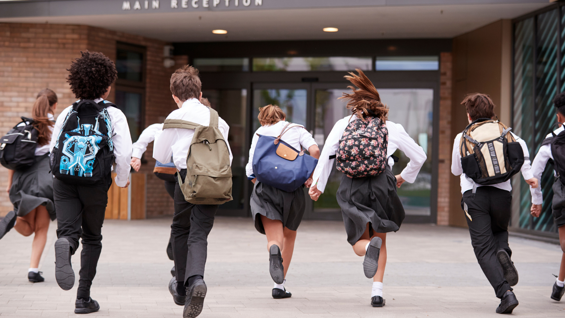 Kids in uniform running into school building