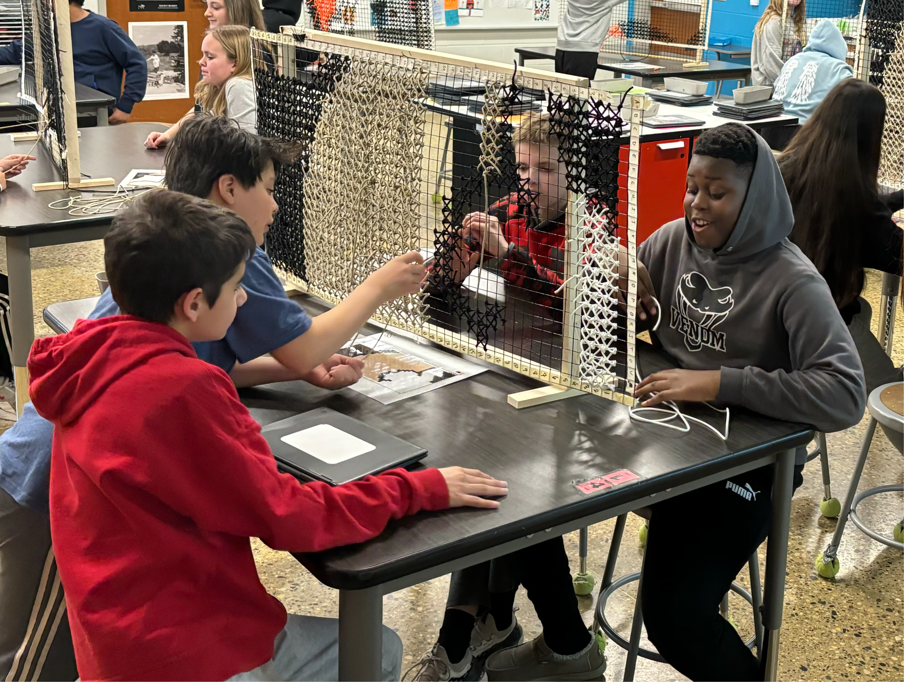 Middle school students in art class doing a large cross-stitch project