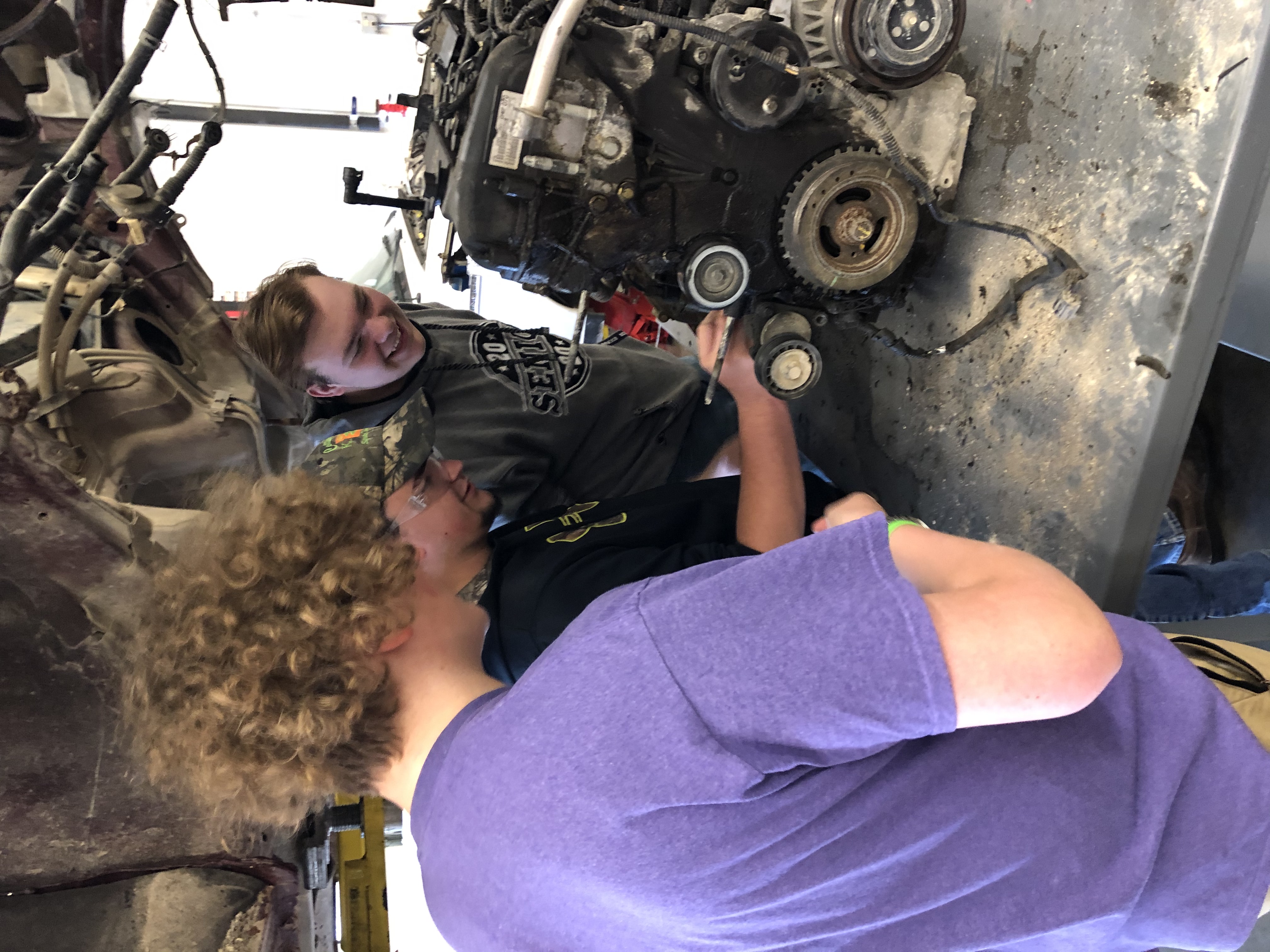 Three students working on an engine