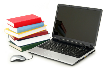 open laptop next to a stack of books