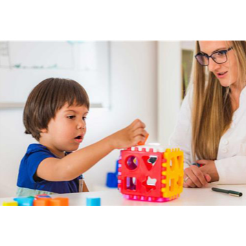 Young student using building blocks while teacher watches